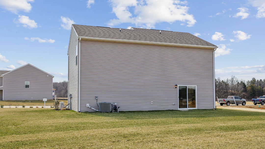 rear exterior view of the home featuring a large well landscaped backyard