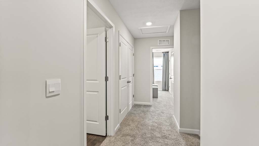 Second level hallway with view of two of the bedrooms and laundry area