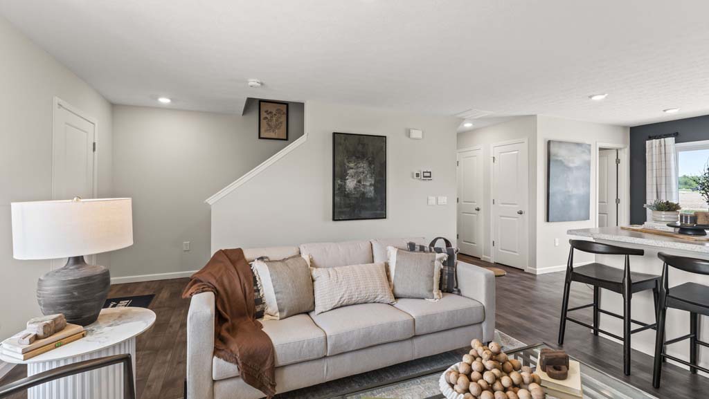 Living room with view of front door, foyer, modern art, and kitchen
