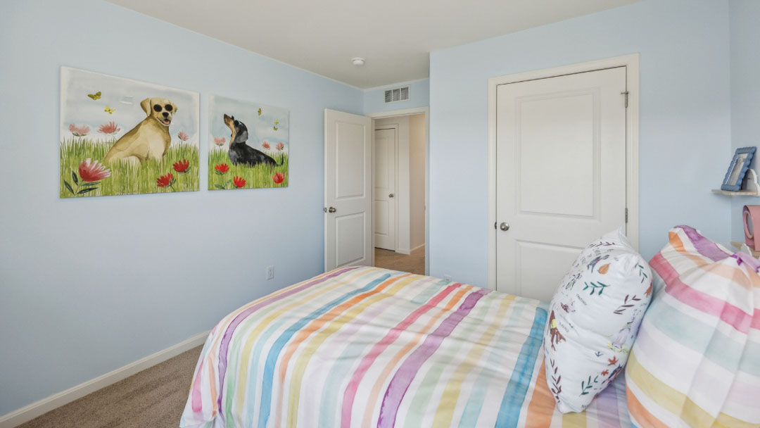 bedroom decorated in colorful decor, featuring light blue walls, white wooden furniture and a window to the right of the bed