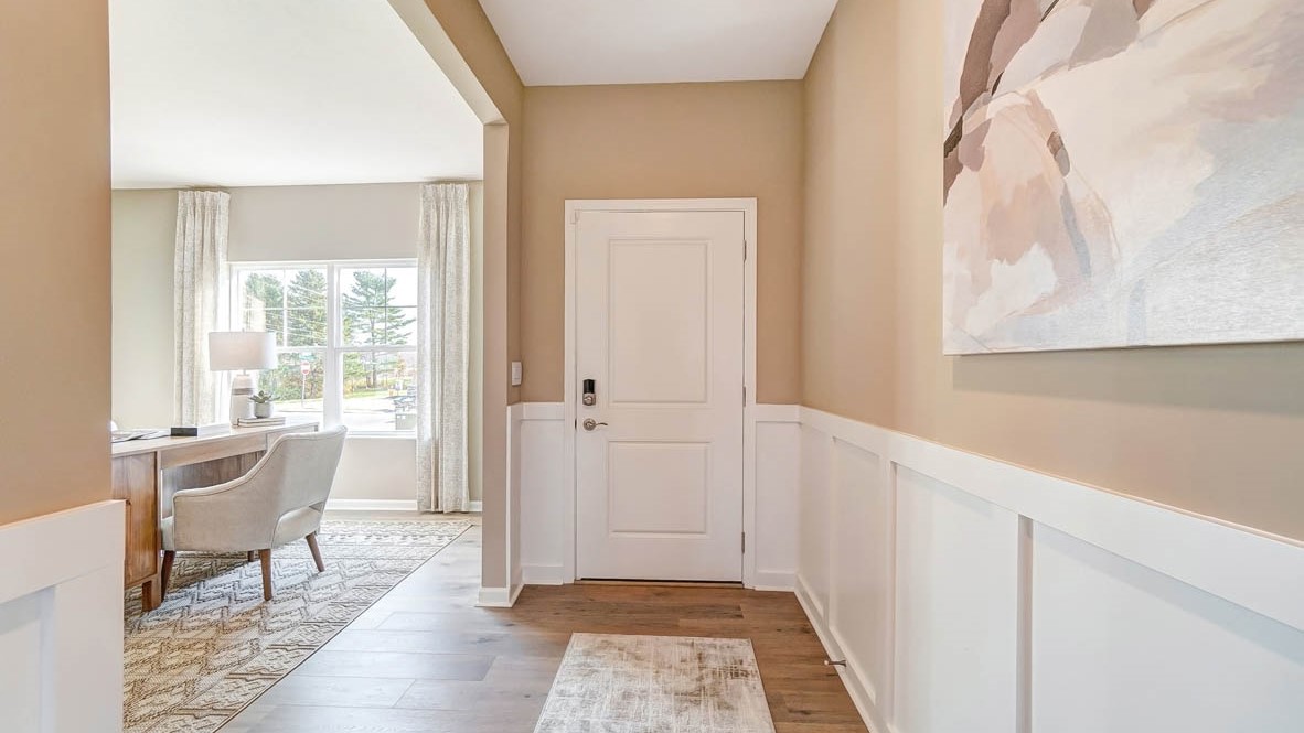 Foyer with front door in frame with office on the side.