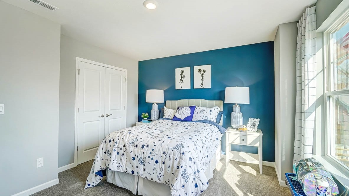 bedroom with large bed, blue bench and cheerleading decorations with bedside tables.