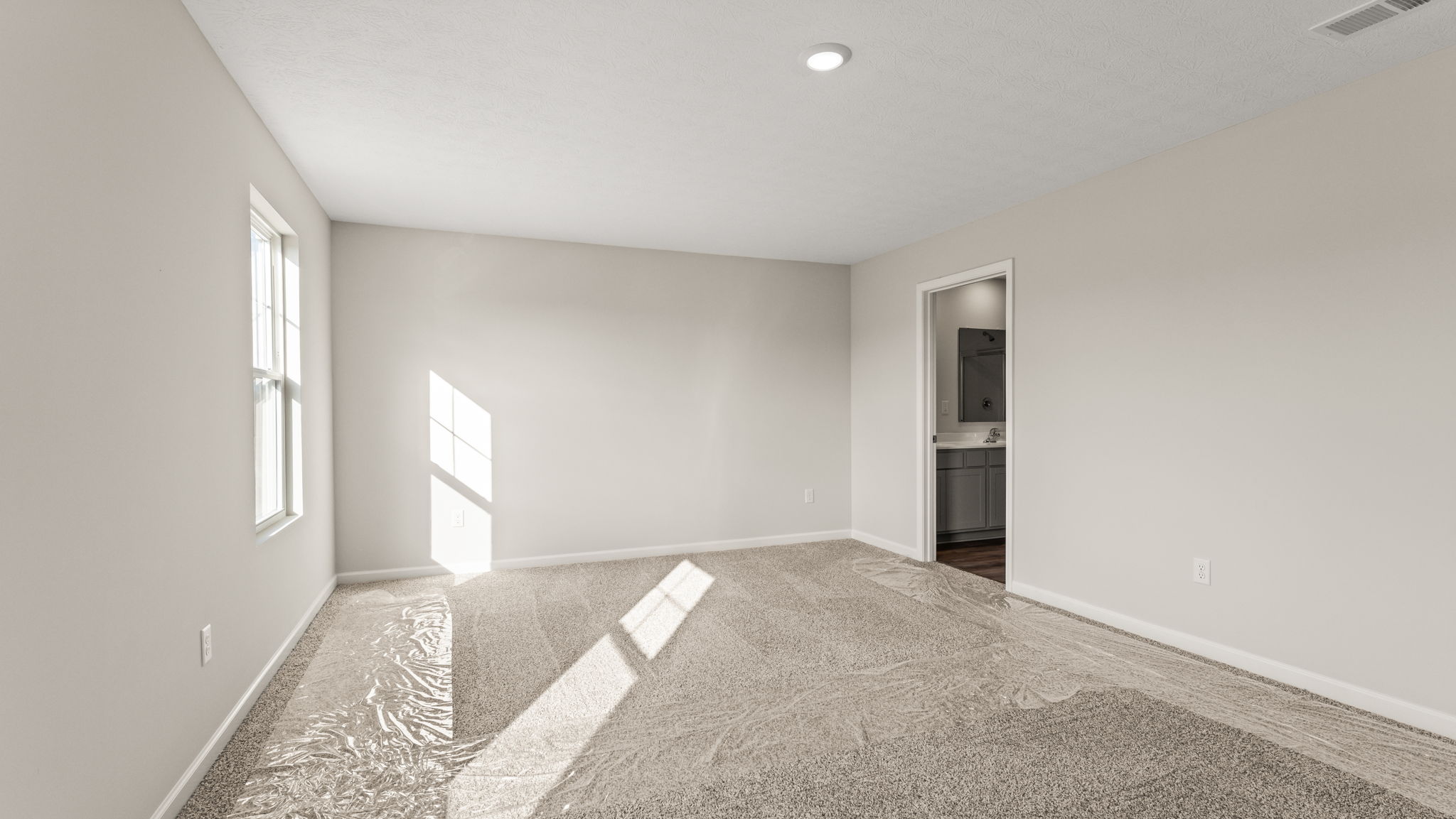 Carpeted primary bedroom with door to bathroom