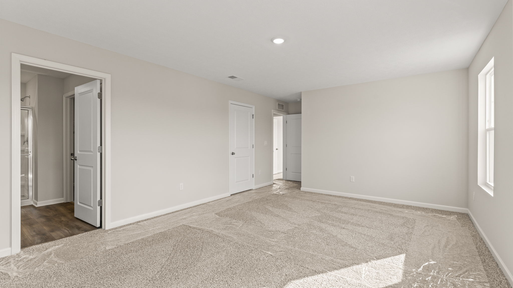 Carpeted primary bedroom with door to bathroom