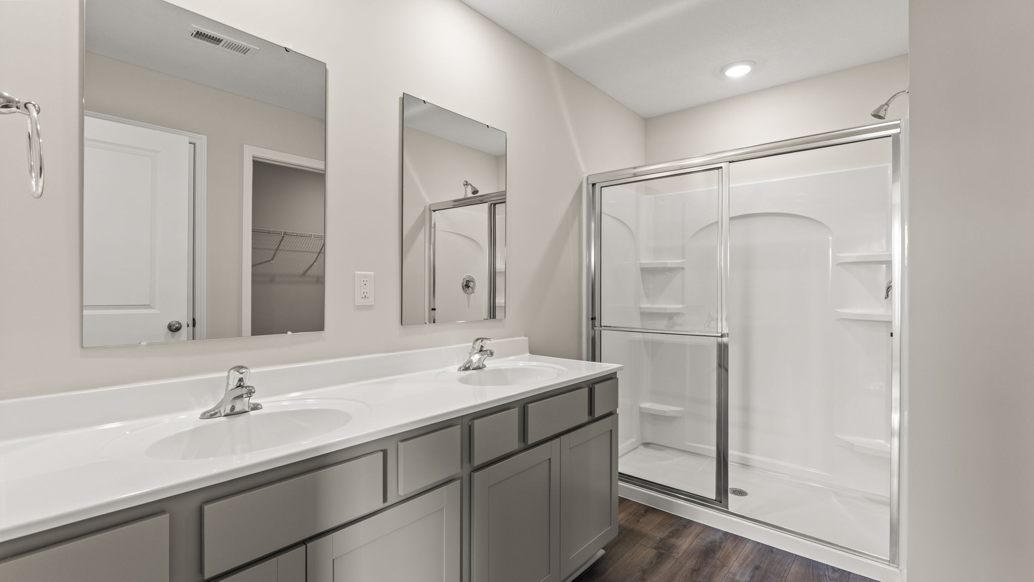 Primary bathroom with dual-sink vanity, mirrors, and walk-in shower