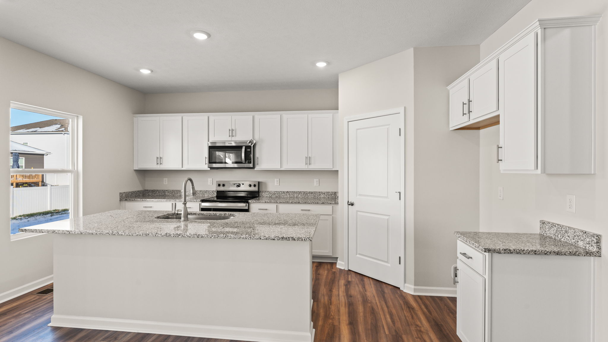 Alternative angle of kitchen with island, microwave, and cabinetry.