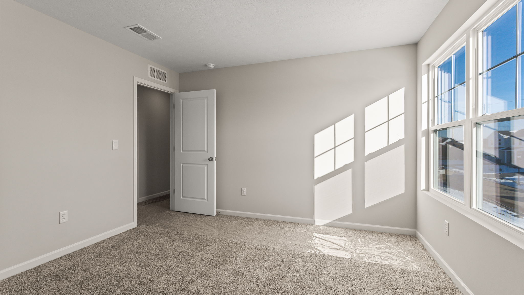 Bedroom with carpet, window, and door to hallway
