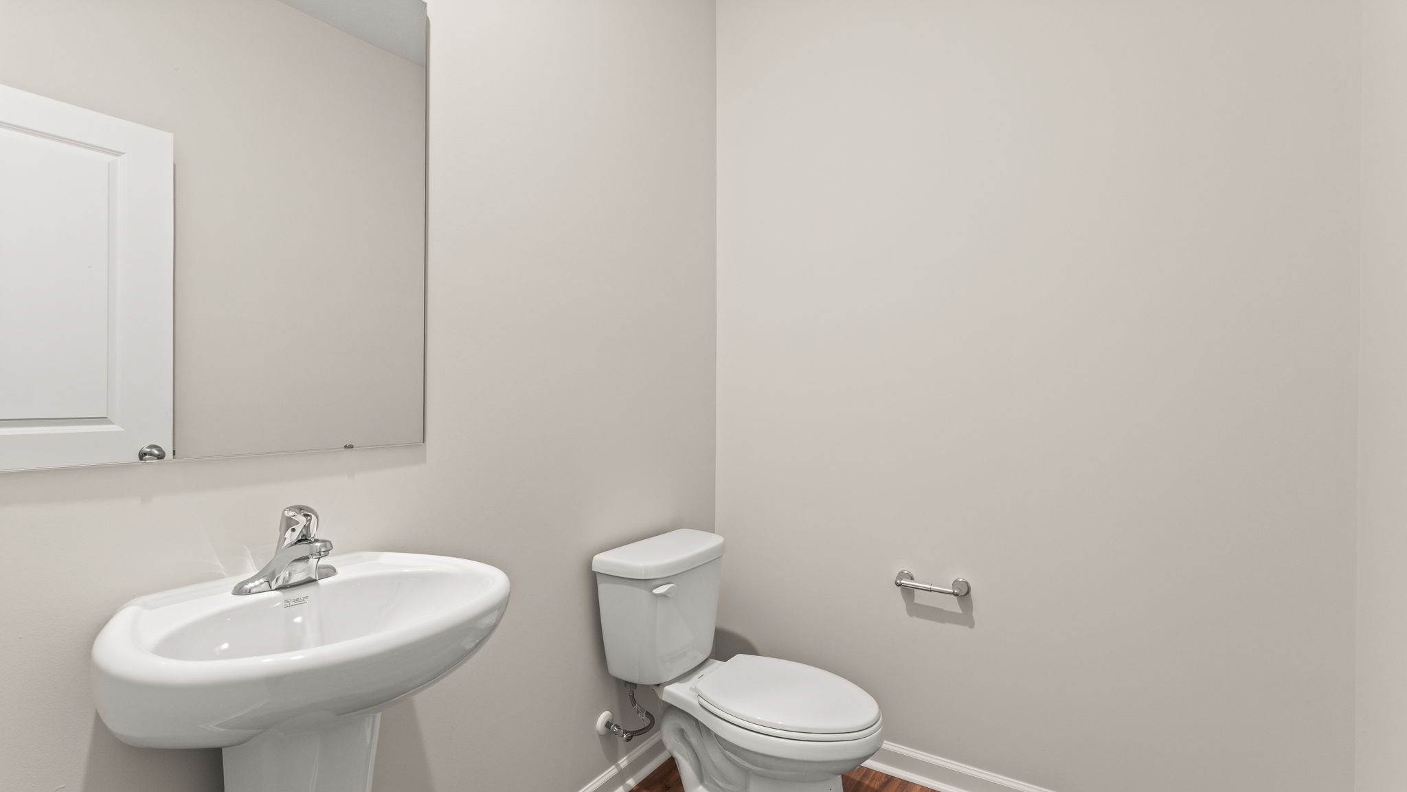 Powder room with toilet, sink, and mirror.