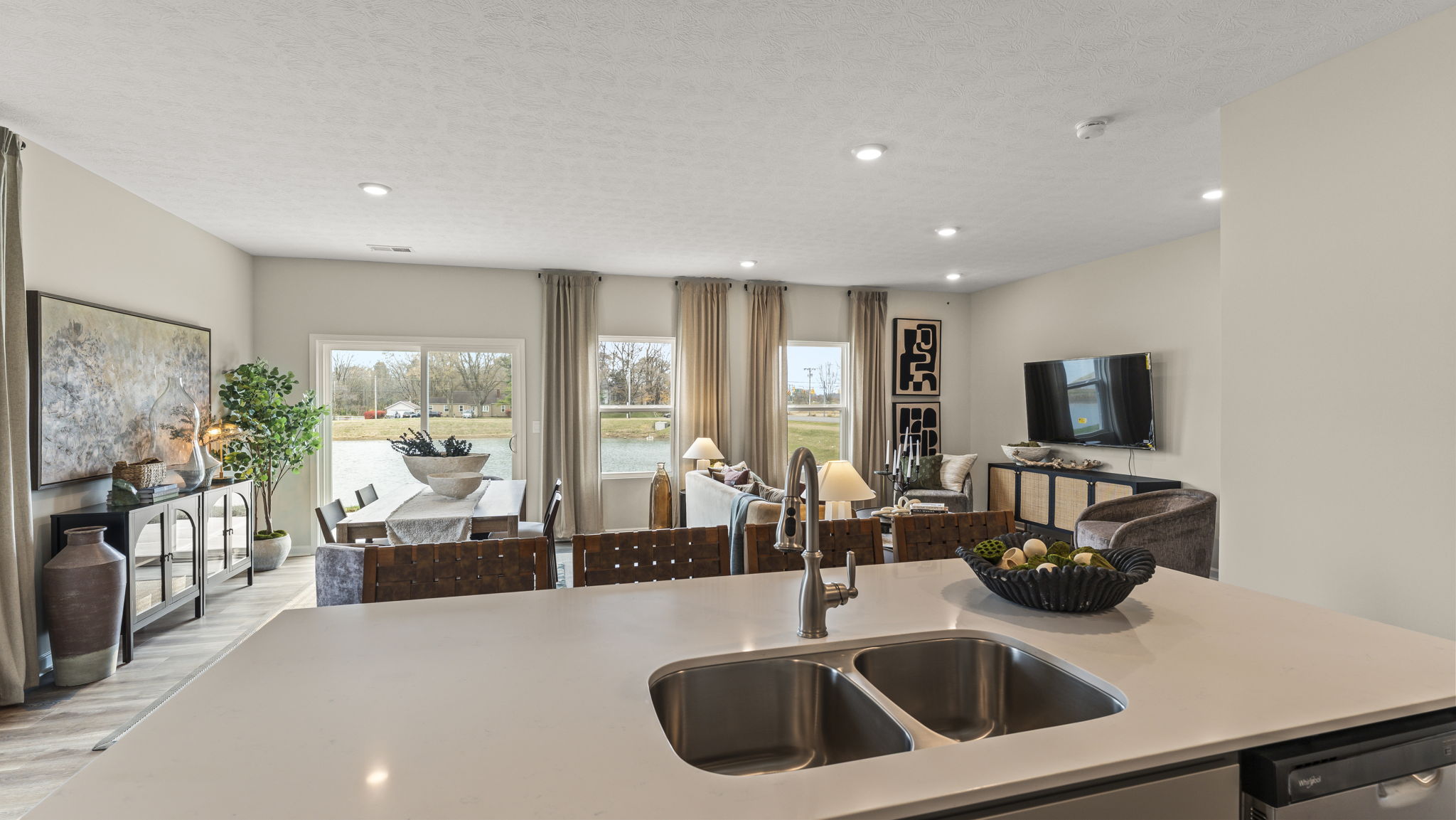 Point of view shot from the quartz kitchen island into the living room with brown, green, and beige tones.