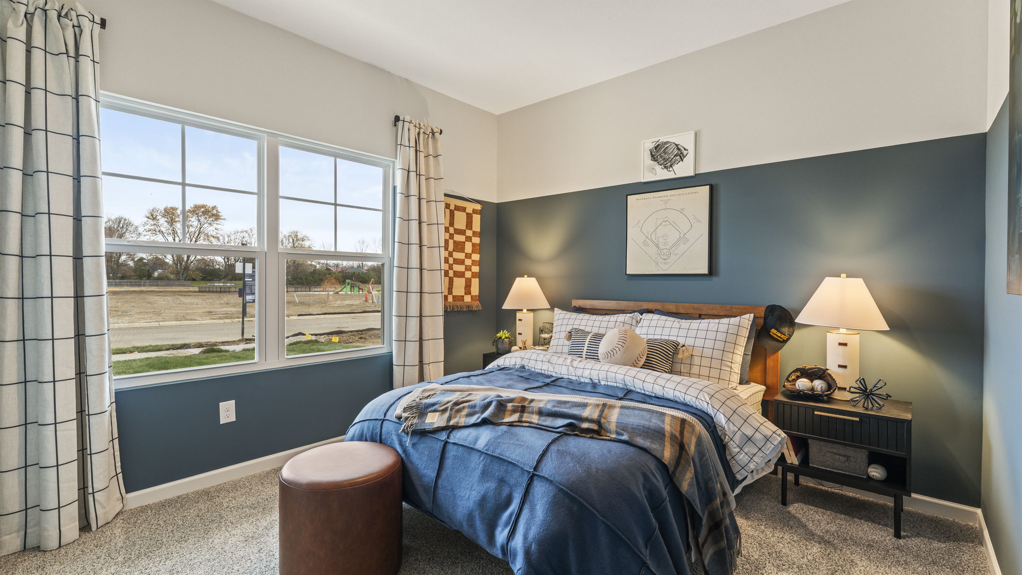 Baseball-themed bedroom with blue and white bedding, two-tone wall paint, and baseball-inspired art on the wall above the bed.