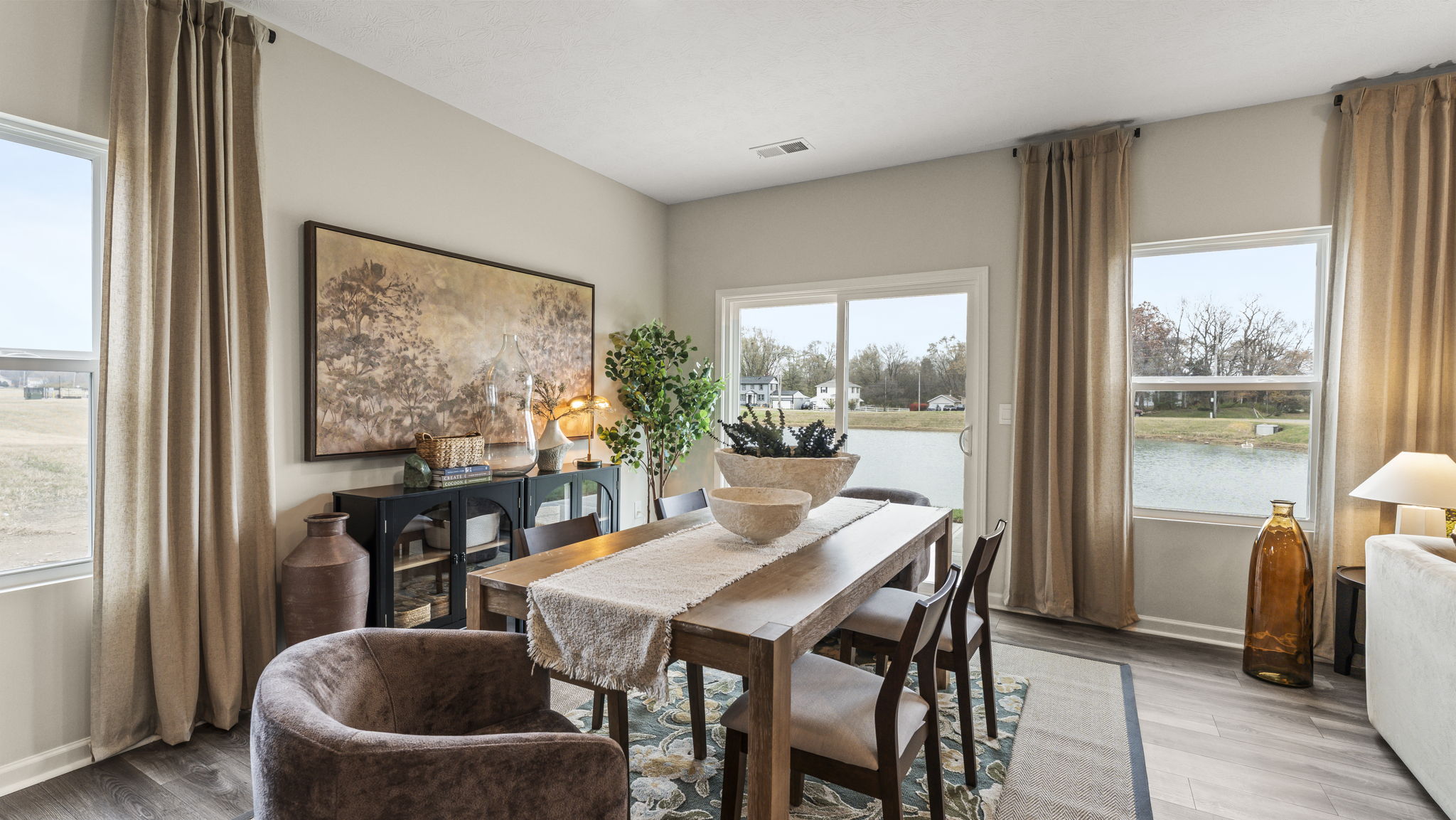 Dining area with earthy tones and wooden table with ceramic bowl centerpiece.