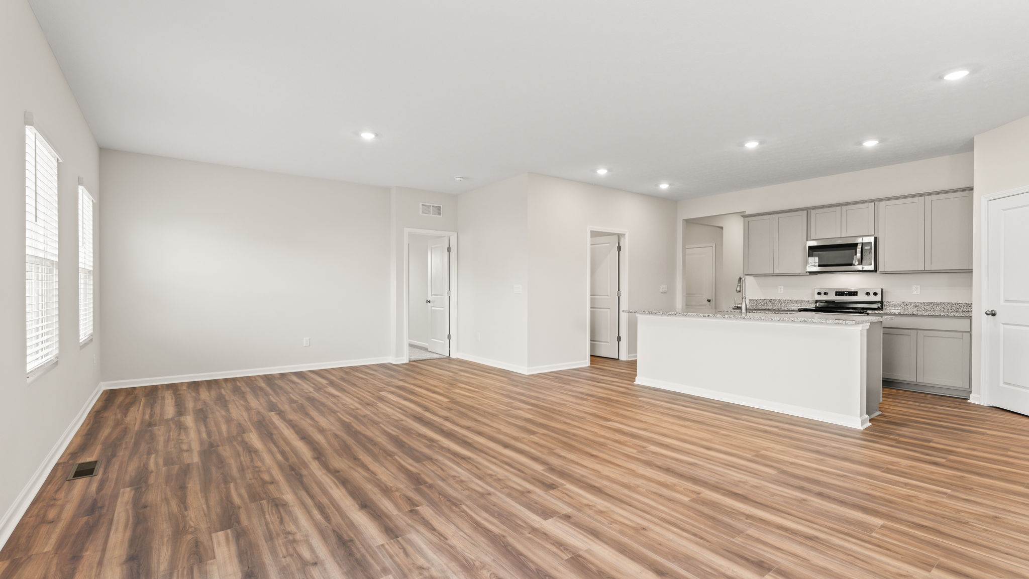 Full great room with primary bedroom on the left and kitchen on the right