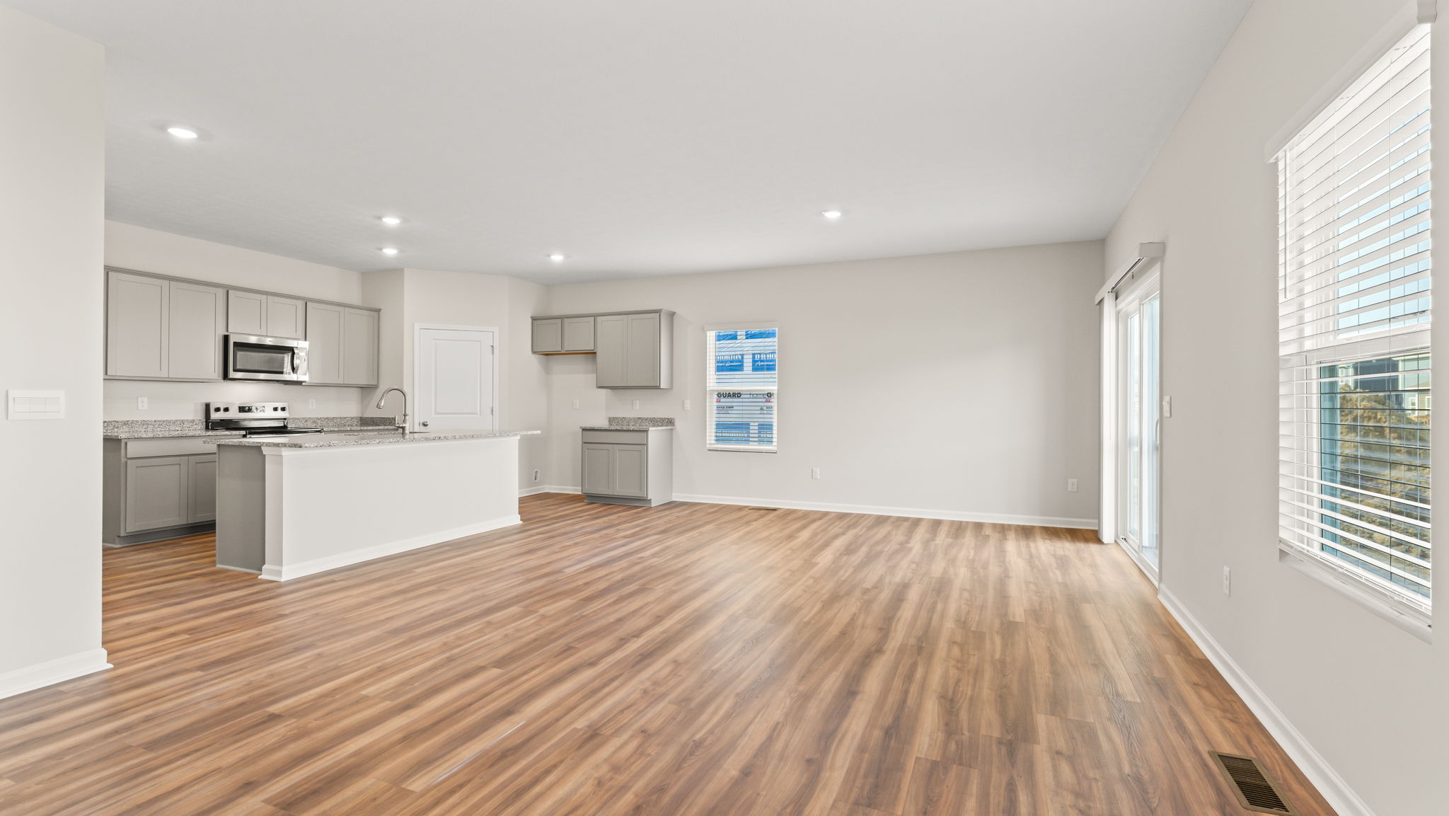 Great room from the corner perspective with kitchen on the left, window and sliding door on the right.