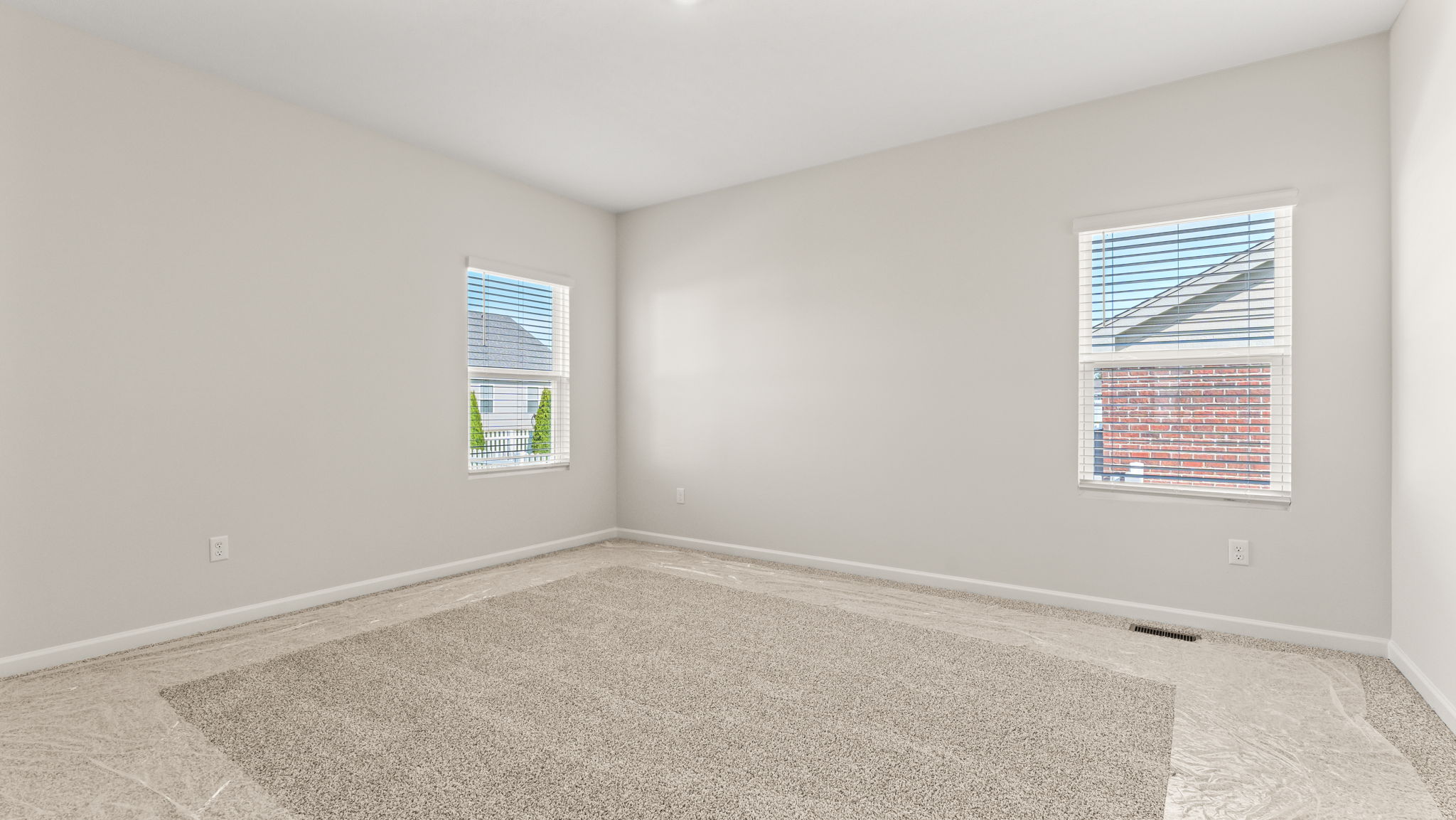 Wide angle image of primary bedroom with carpet and two windows