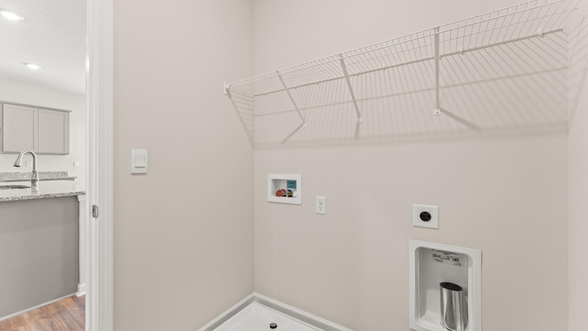 Laundry area with washer/dryer inlets and wire rack shelving