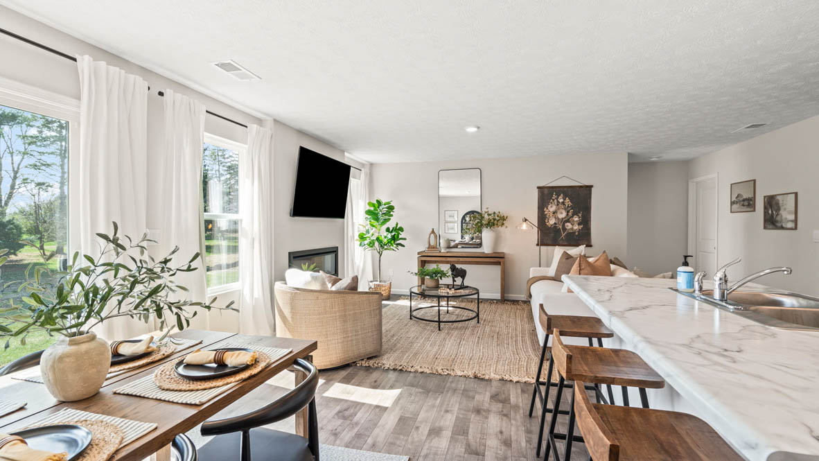 Modern open-concept great room with white cabinets in kitchen and white couch.