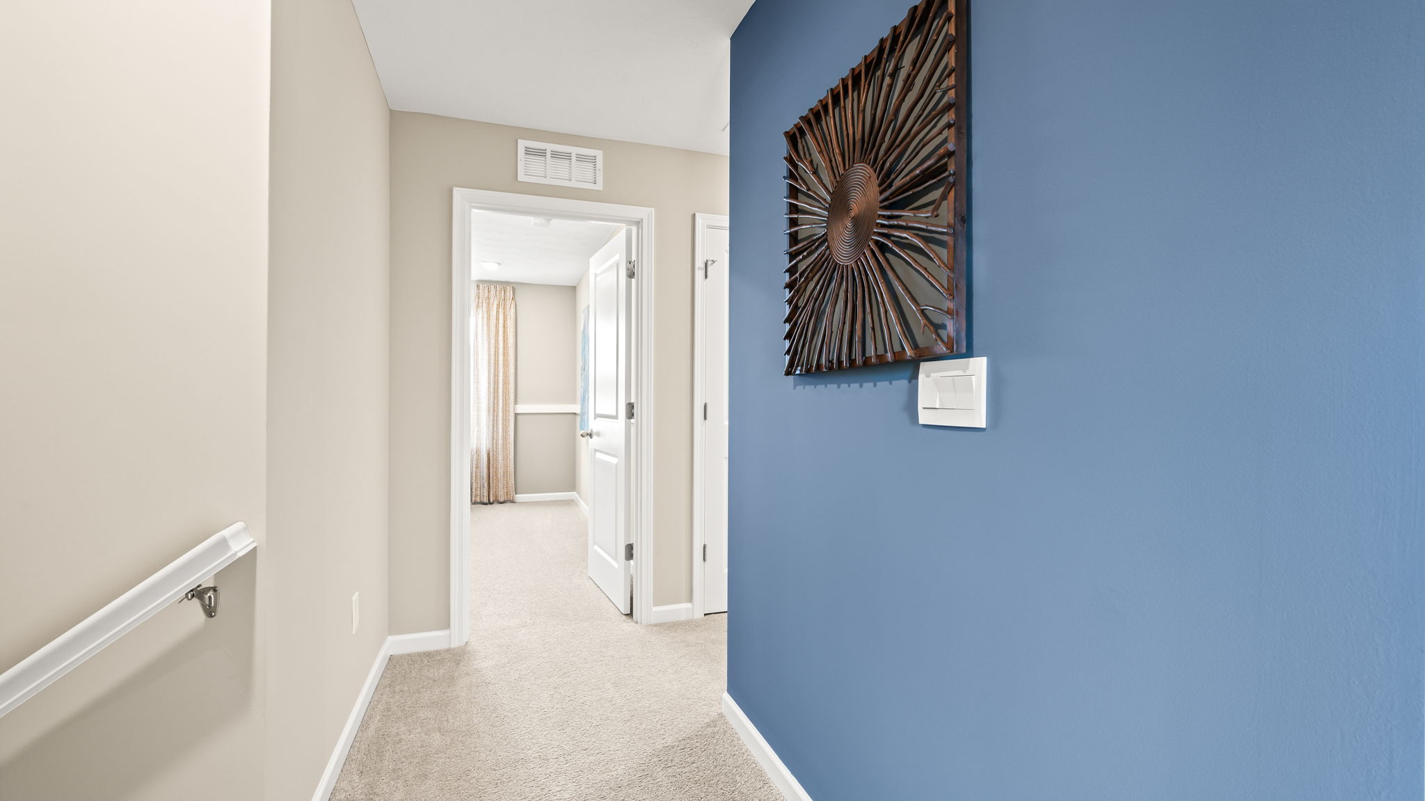 Open closet beside a bright hallway leading into a bathroom with tiled floor, shower, white doors, and a small bench.