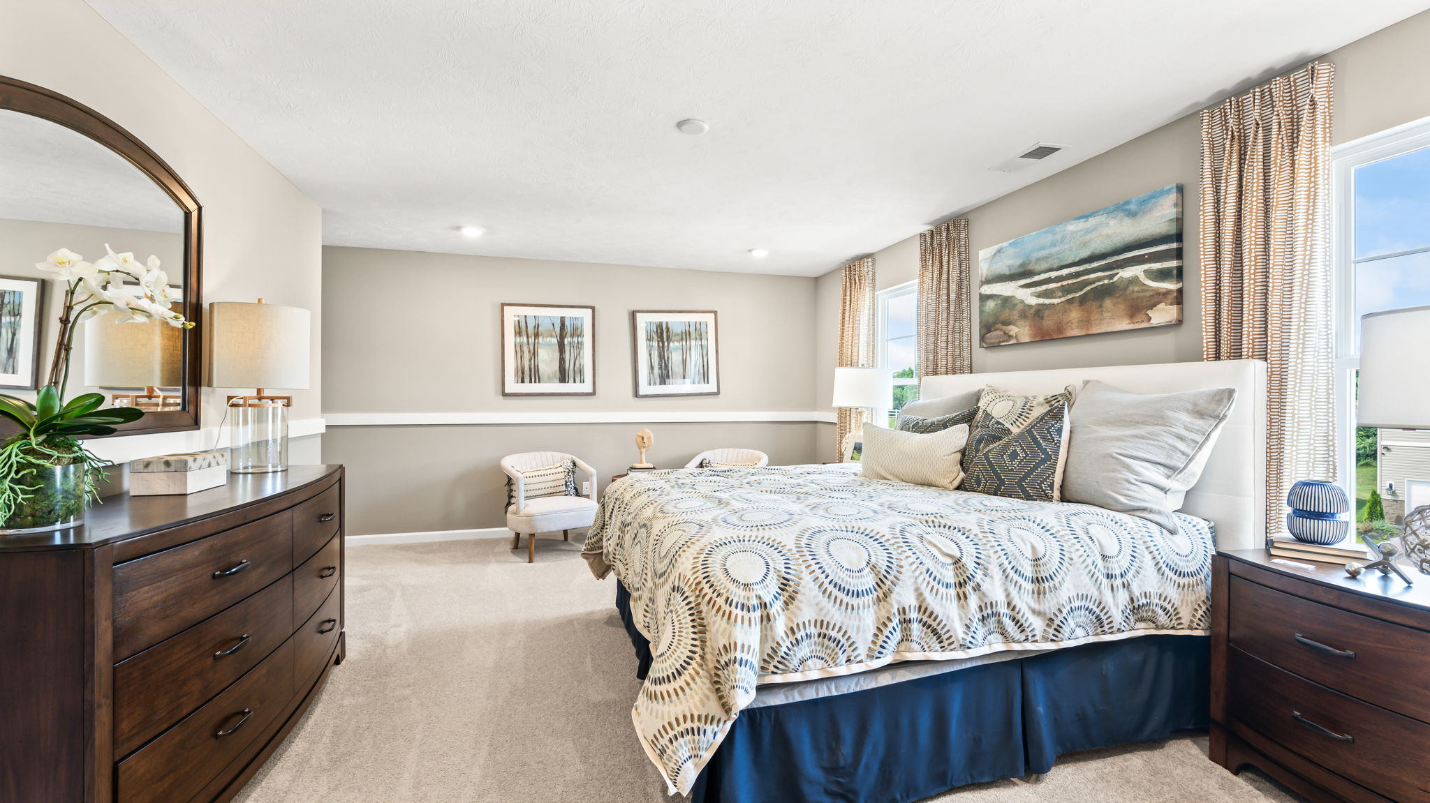 Carpeted upstairs hallway beside a blue accent wall with sunburst wall art, white handrail, and open bedroom doorway.