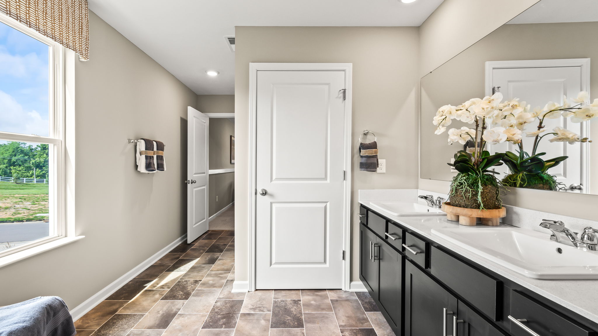 Close view of a white shower with sliding glass doors, chrome trim, corner shelves, showerhead, and towels hung across the door.
