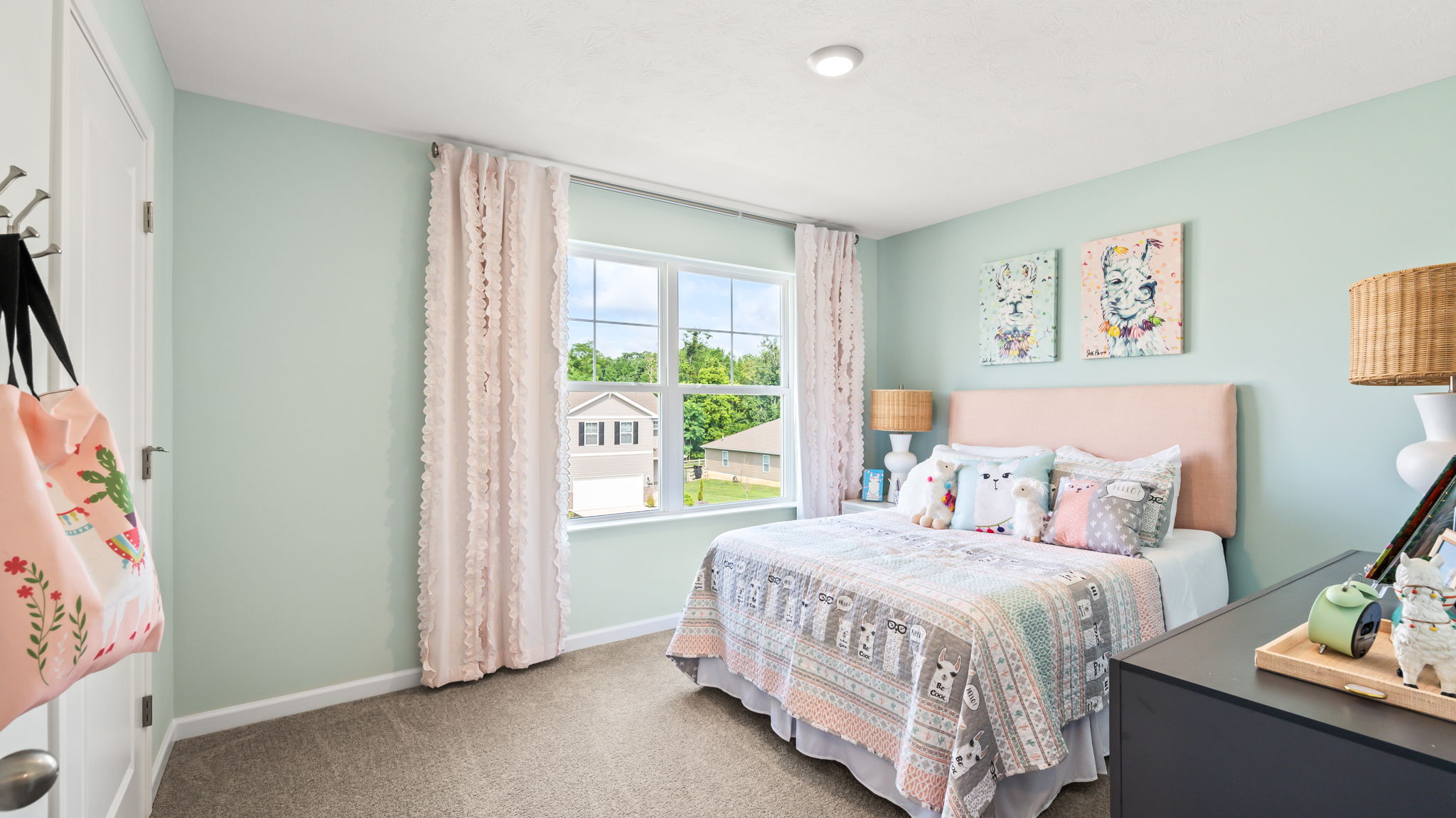 Carpeted upstairs hallway with open doors leading to a mint-green bedroom and a bathroom with a tub and striped shower curtain.