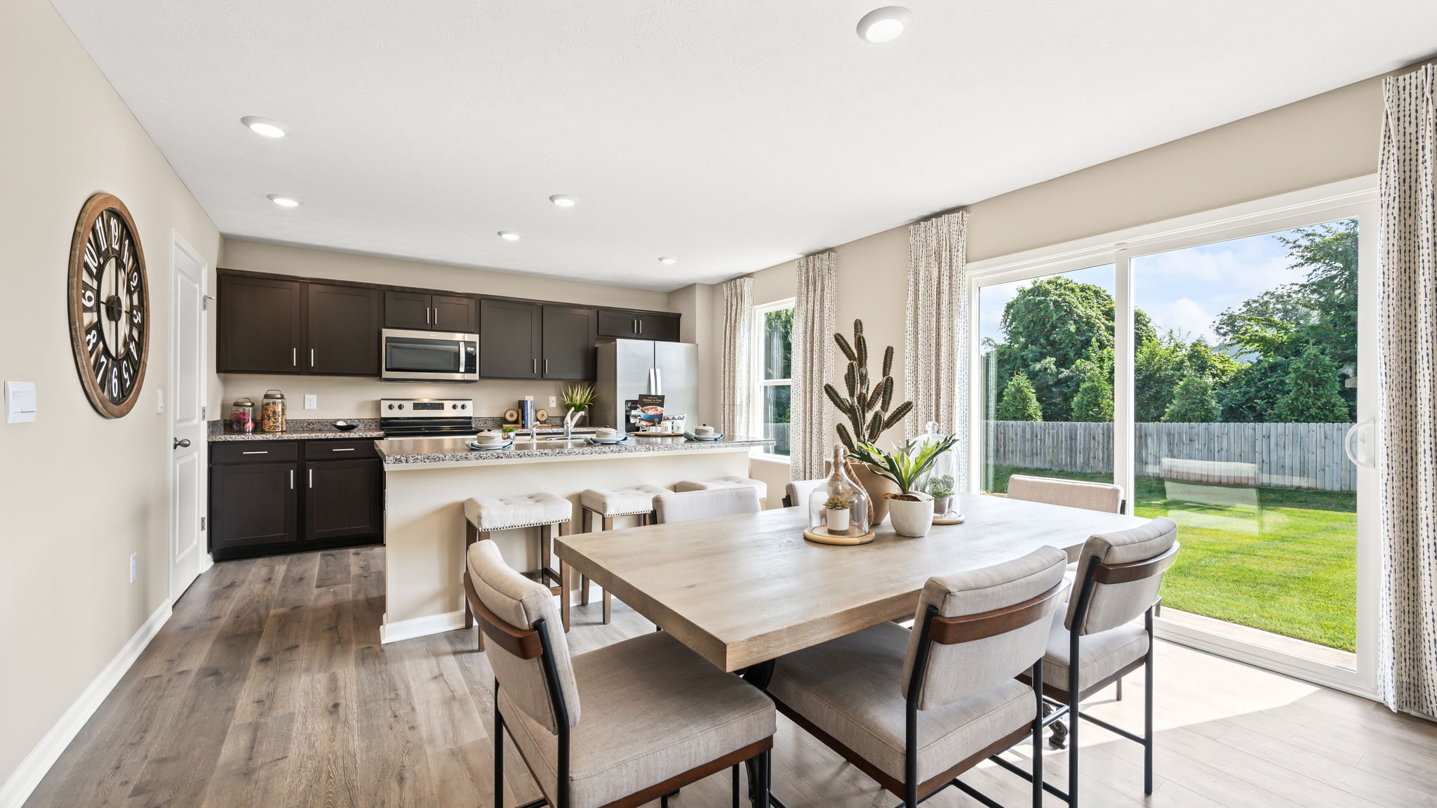 Open dining area with a rectangular table for six beside sliding glass doors, overlooking a kitchen with a breakfast bar.