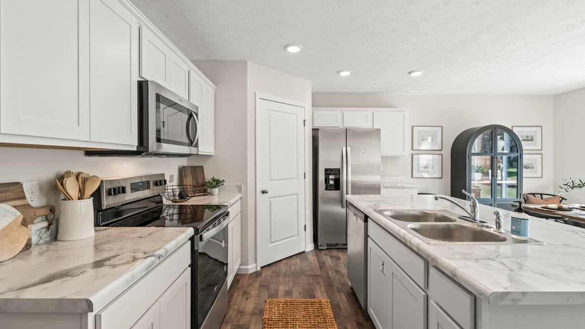 Shotgun view of kitchen with island and stainless steel appliances and white cabinets.