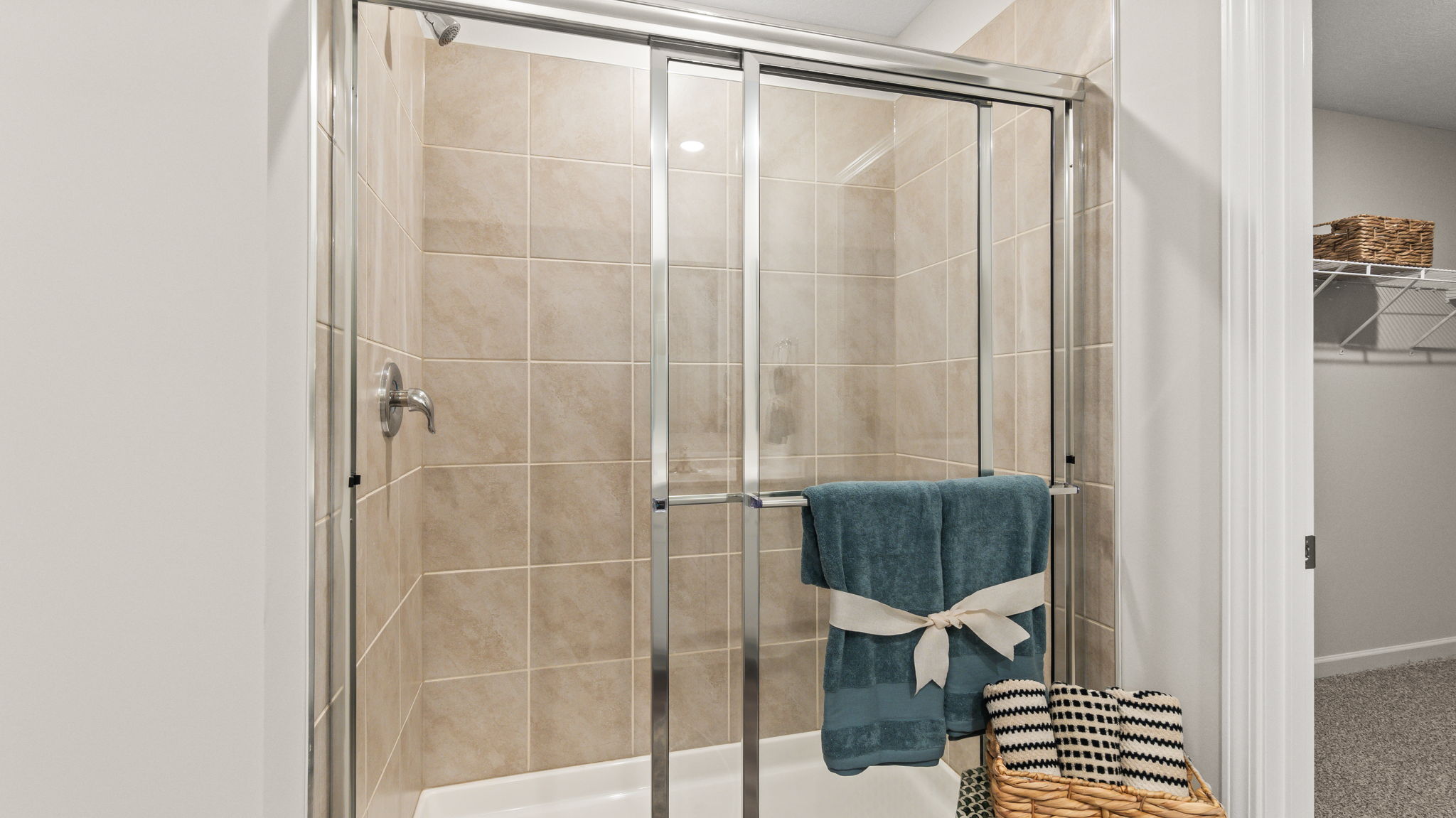 Primary bathroom with with cultured marble vanity, two mirrors, plant, and walk-in closet. Tiled walk-in shower.