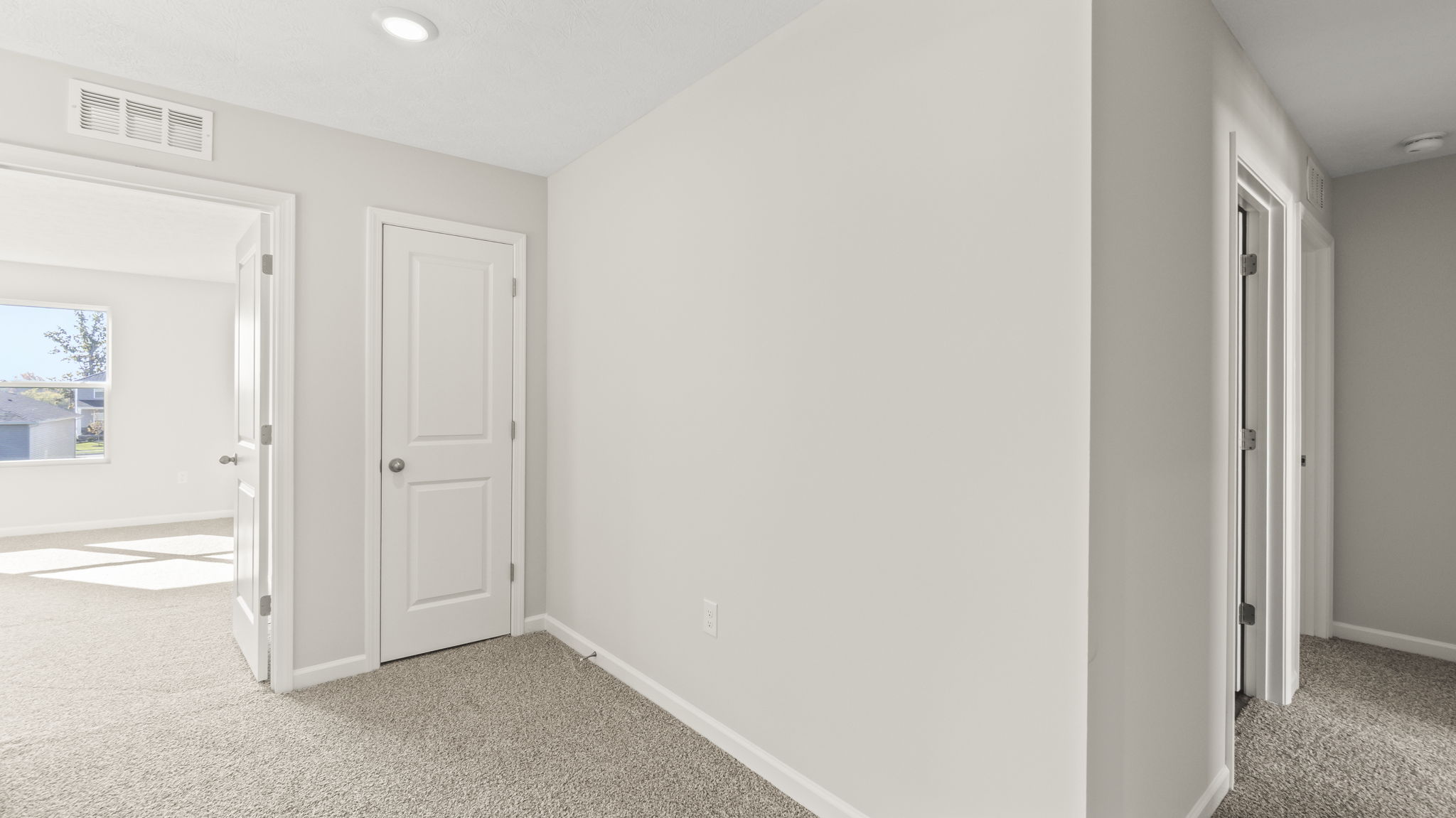 Upstairs landing with carpet and view of bedrooms and storage space.