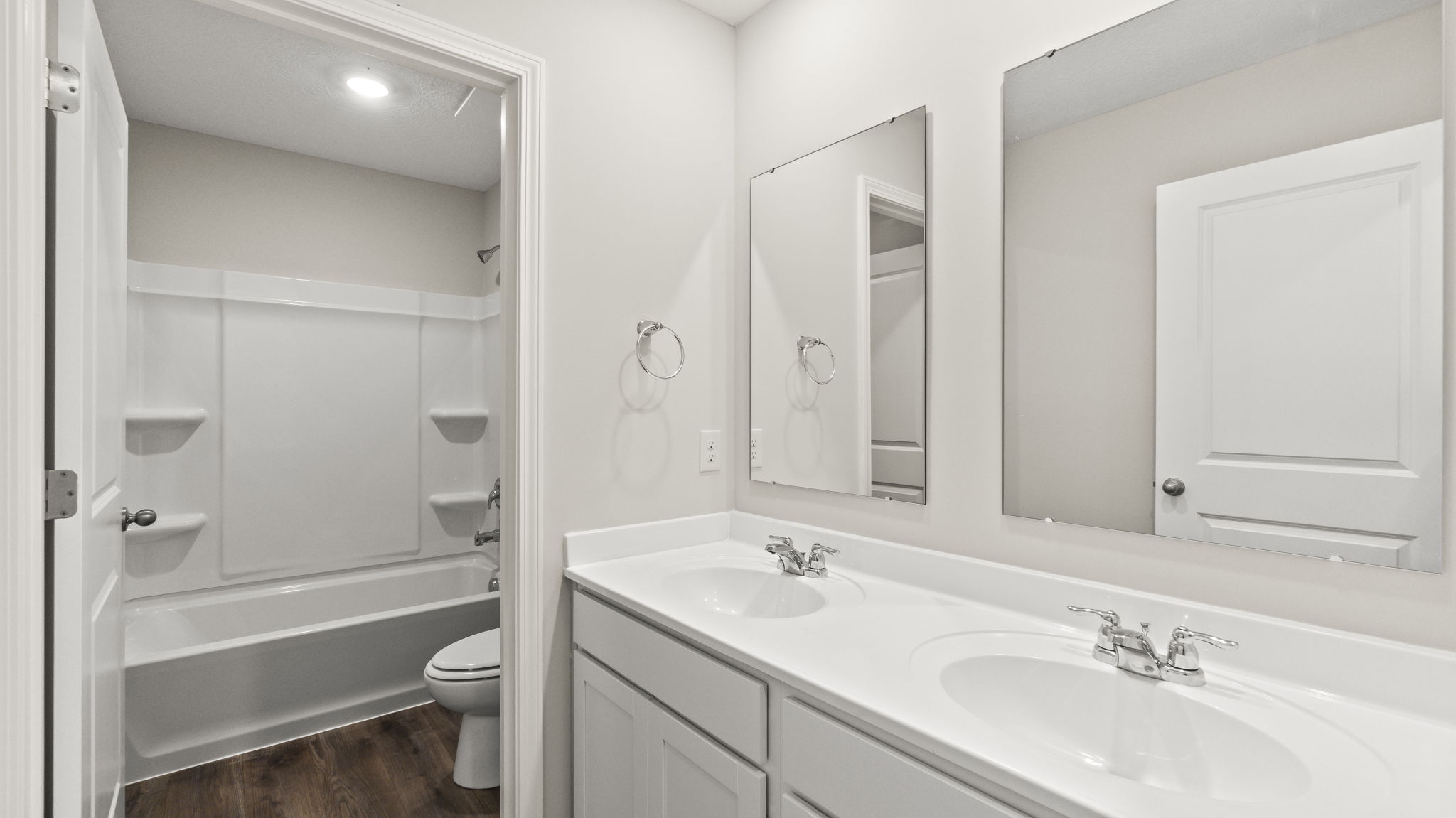 Upstairs bathroom with dual-vanity sink with mirrors, toilet, shower and tub combo.