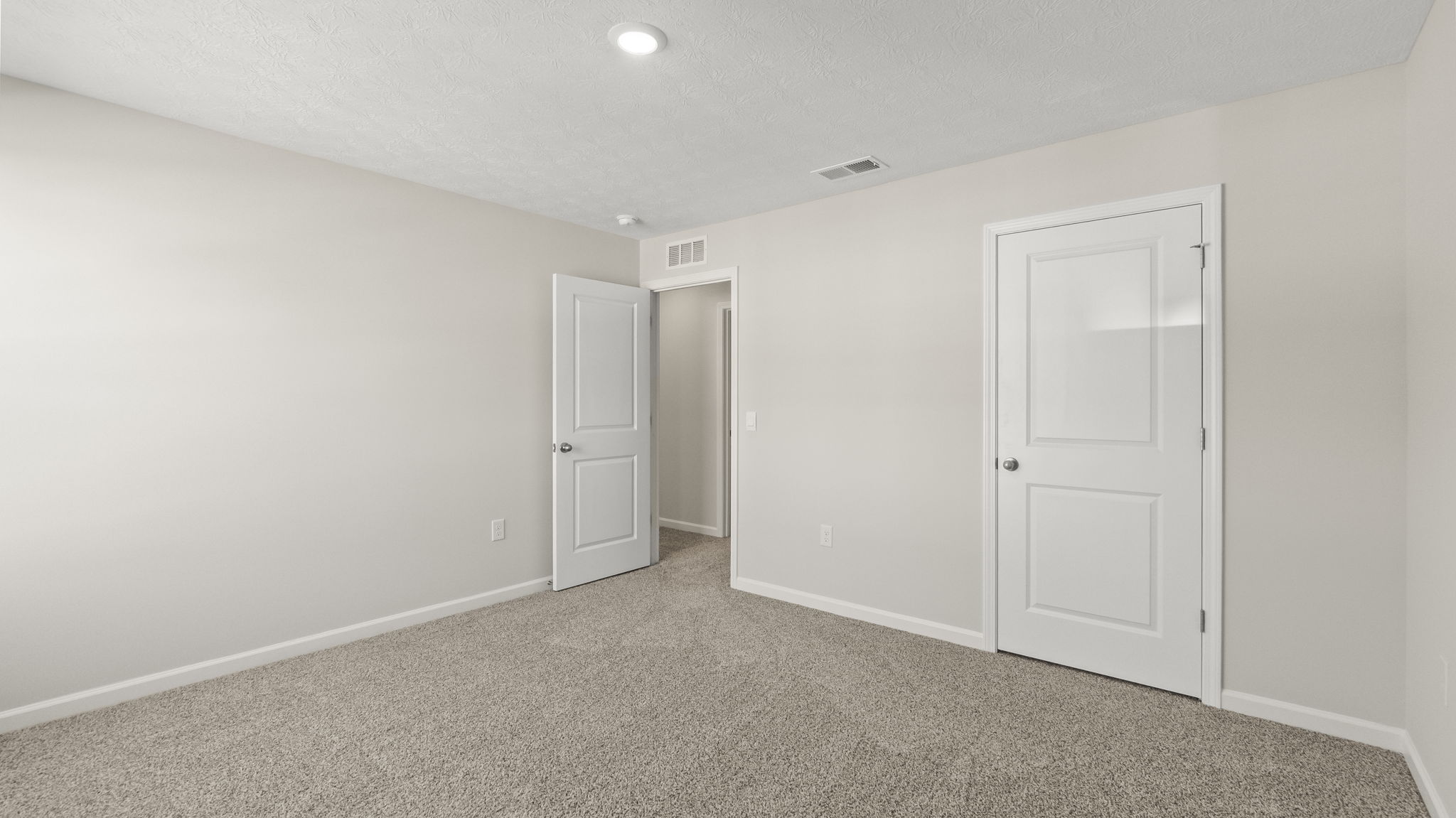 Carpeted bedroom with door to hallway and closet