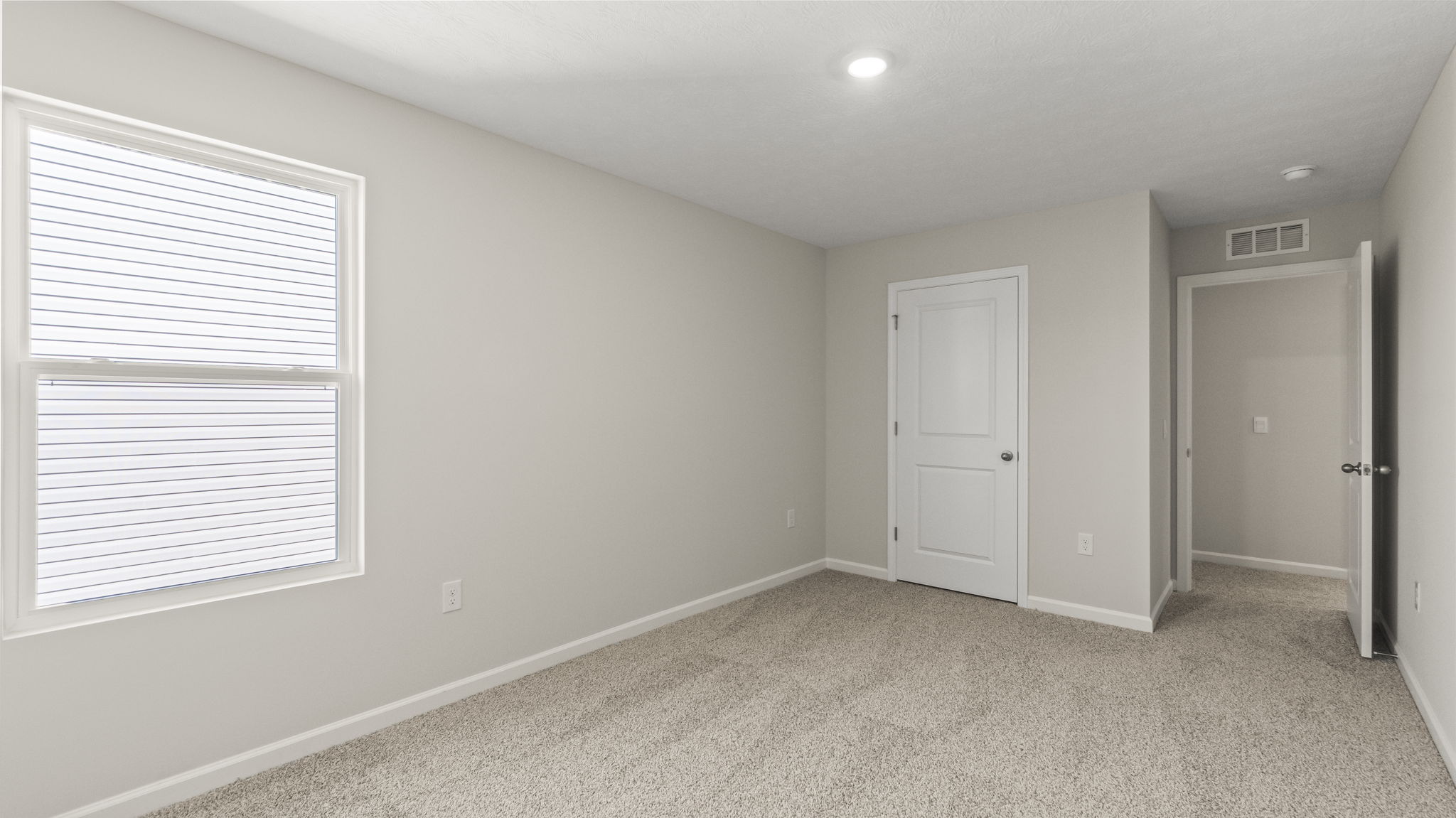 Carpeted bedroom with door to hallway and closet