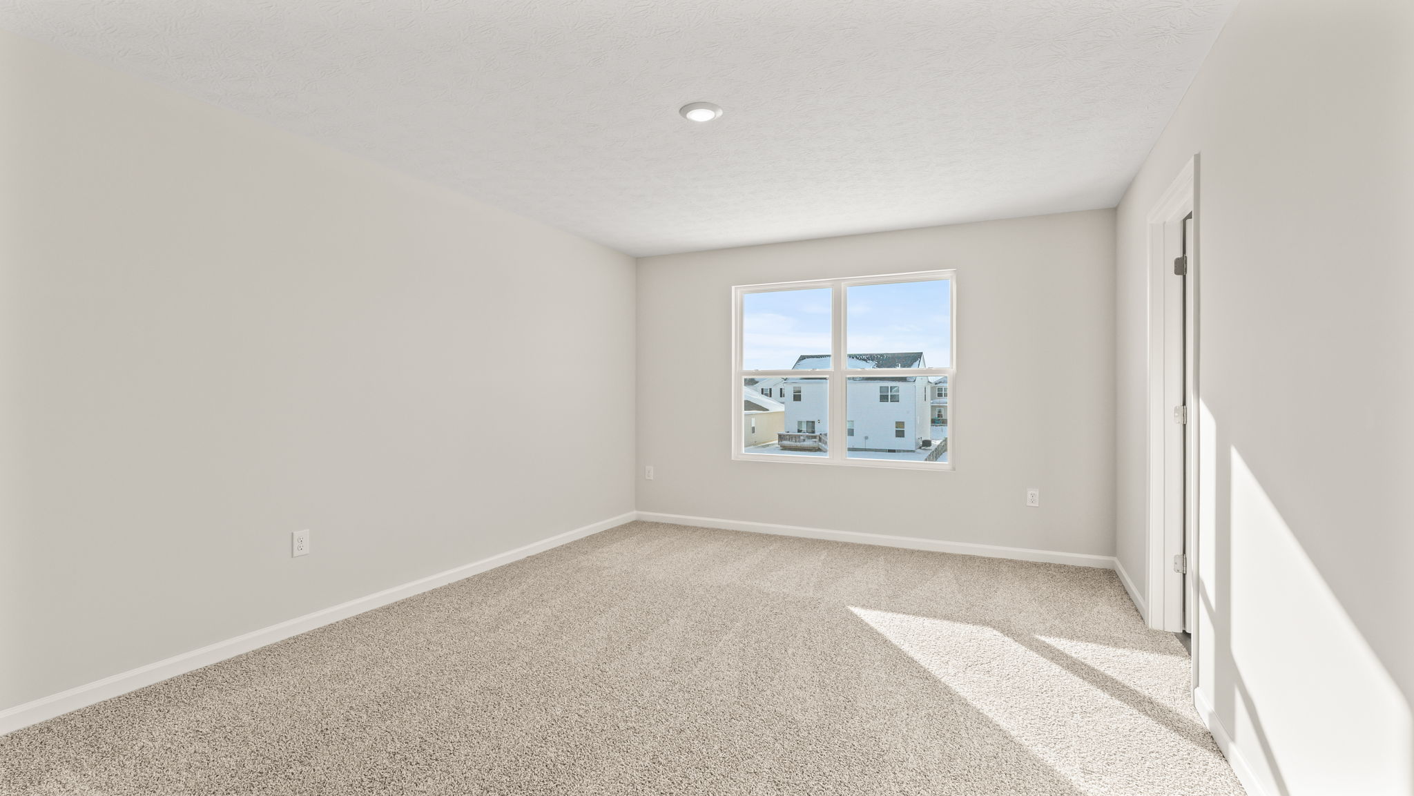 Primary bedroom with carpet, window, and outlets.