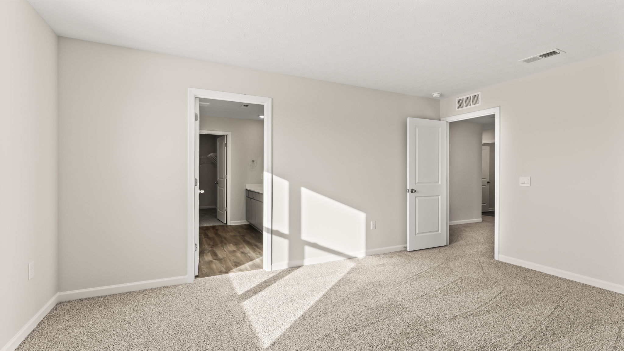 Primary bedroom with doors to the bathroom and hallway