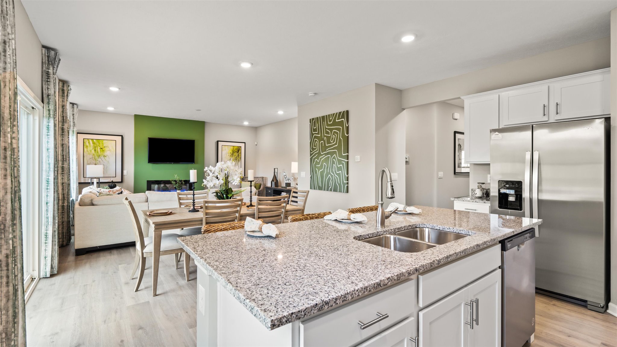 corner view of kitchen island, dining area, and living room with modern art pieces throughout.