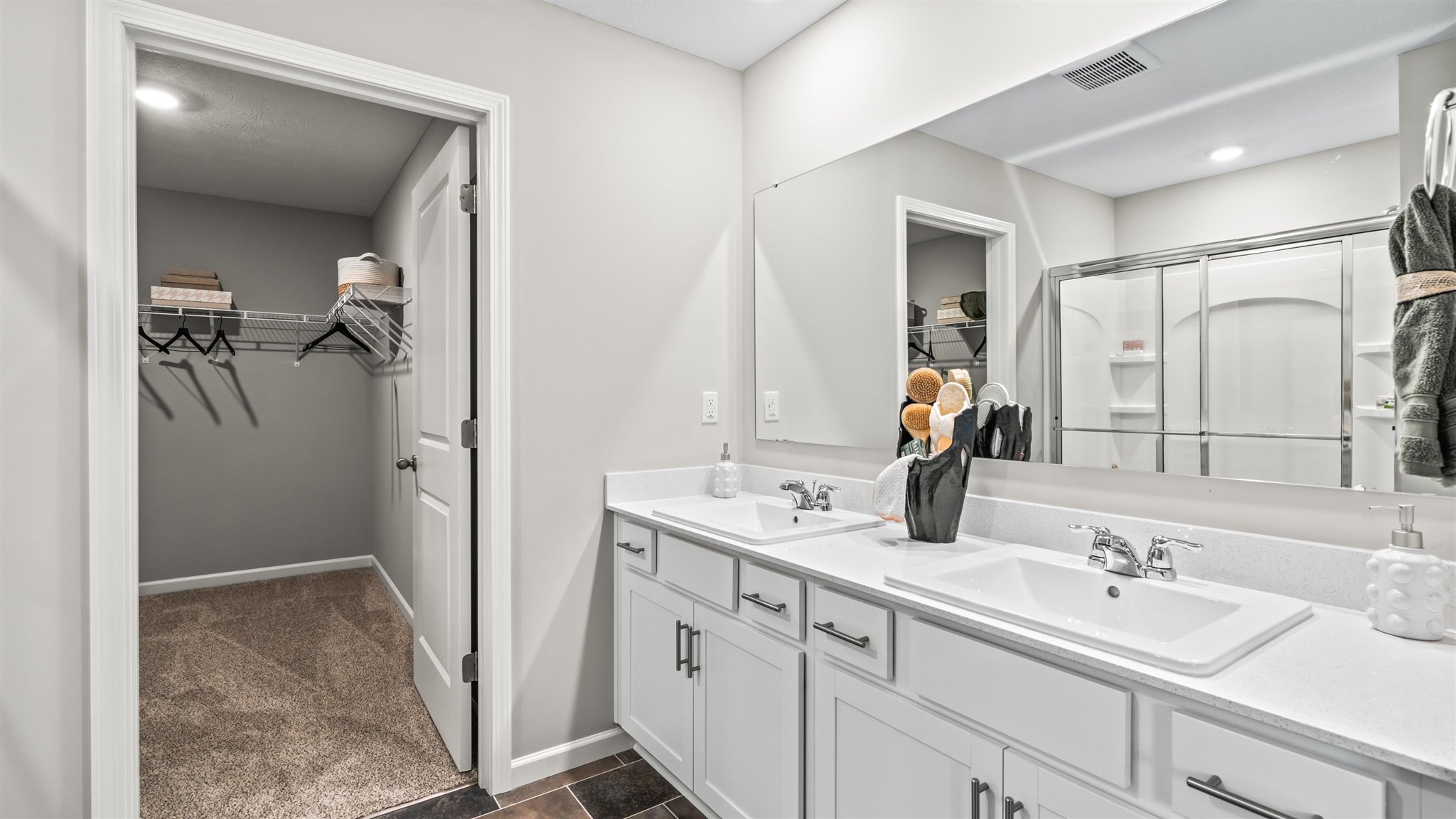 Dual vanity sinks in primary bedroom and and view of walkin closet.