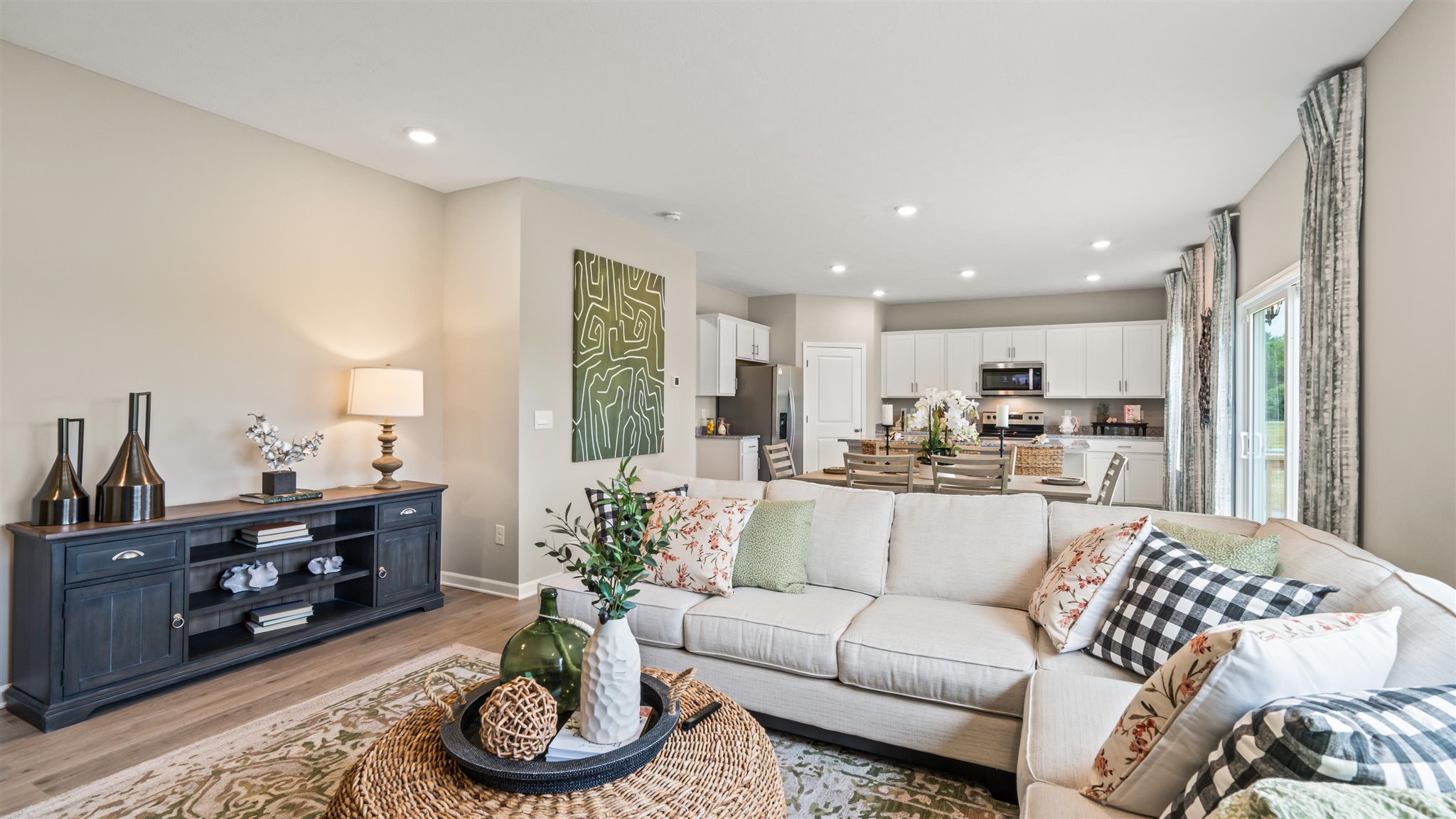 Living room with modern art accents and large lush couch with the great room in the background.