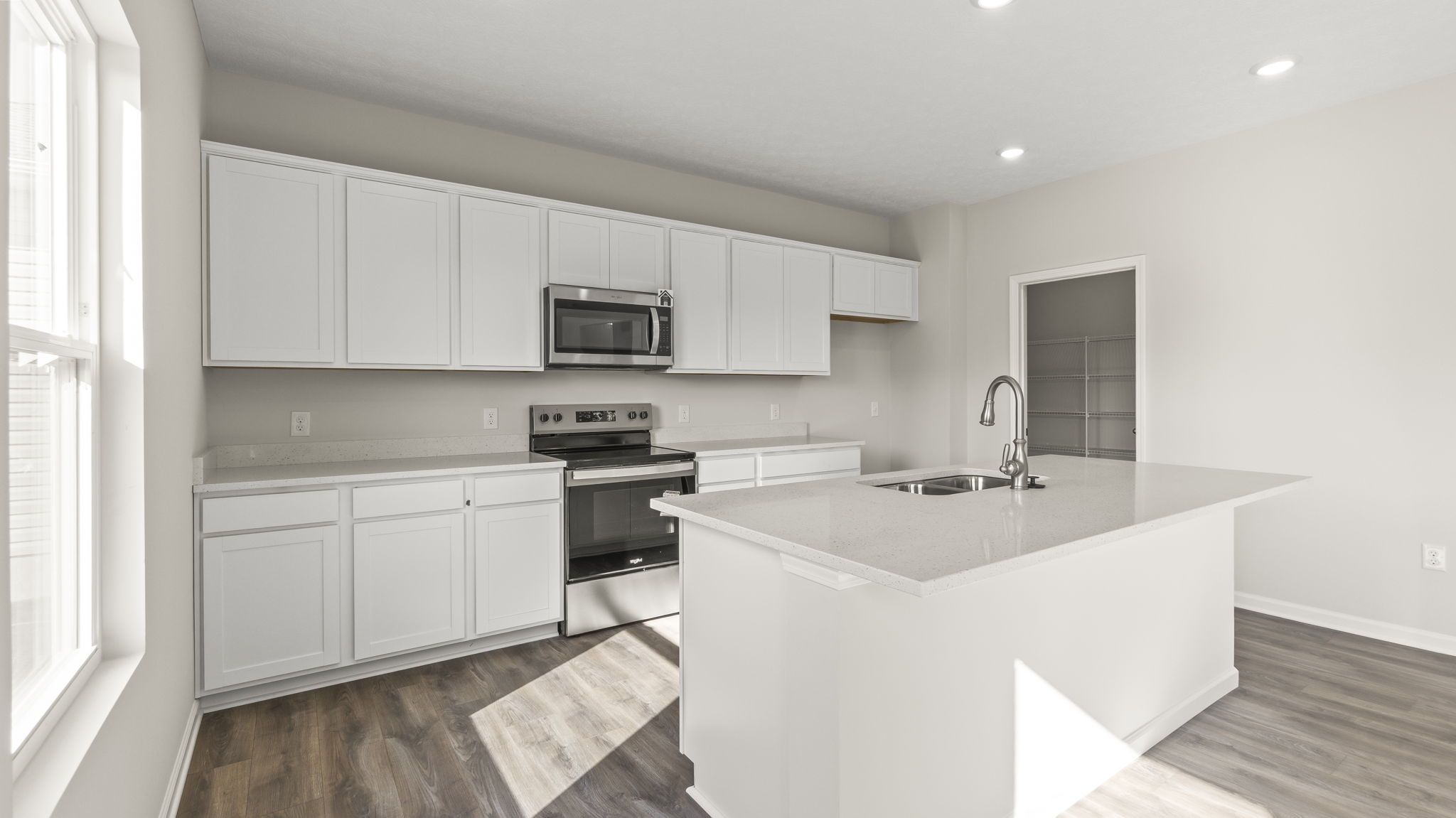 Three-quarter angle of kitchen with white cabinetry, marble countertops, and white cabinetry