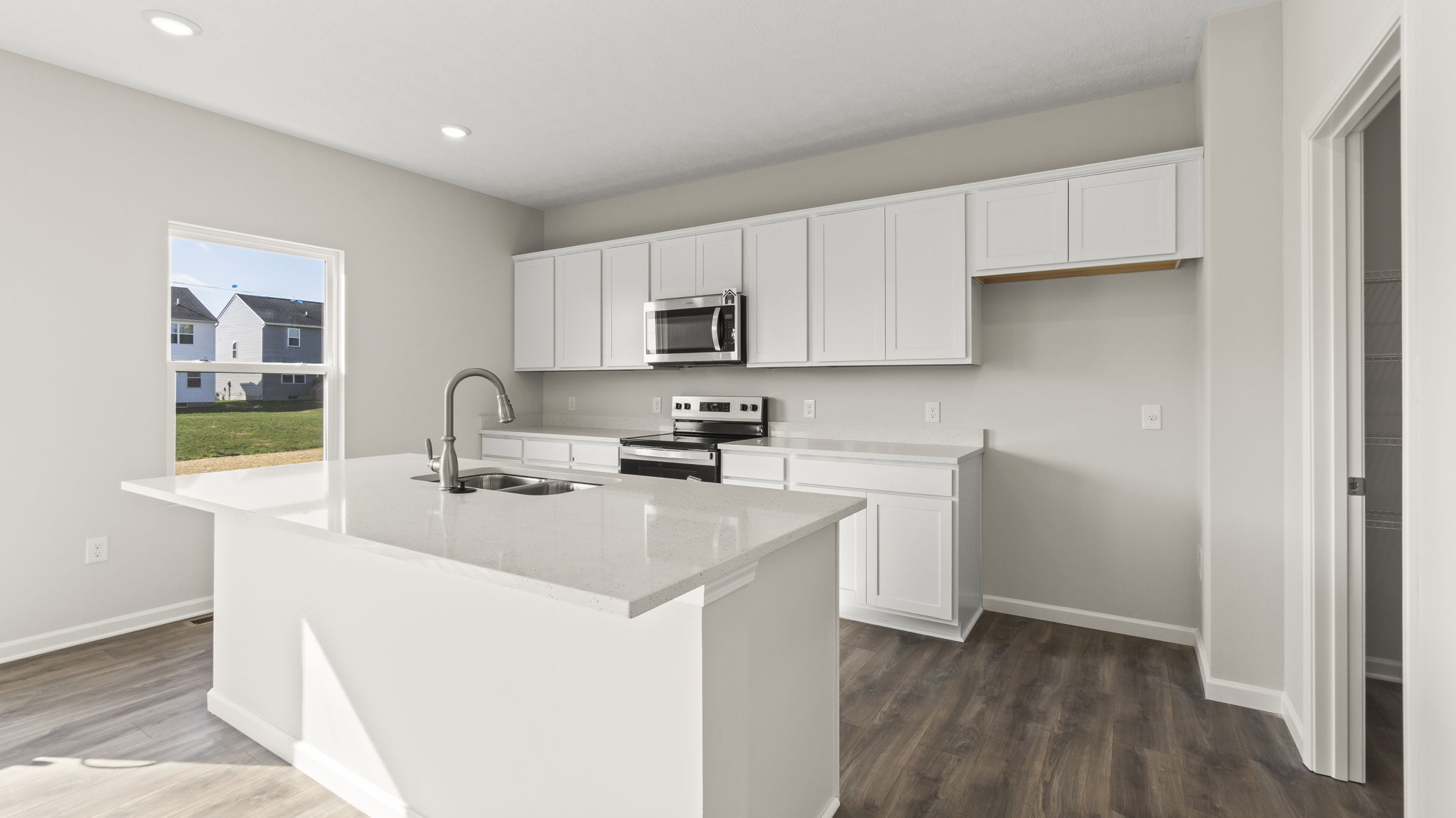 Three-quarter angle of kitchen with white cabinetry and marble countertops.