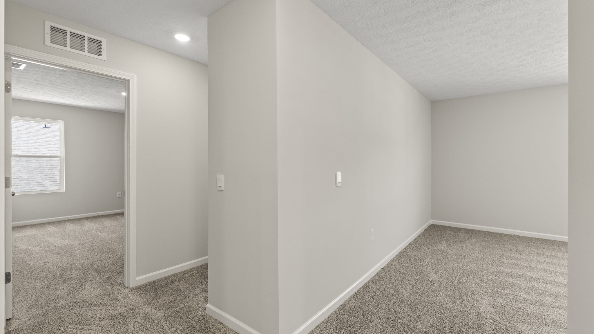 Upstairs landing with carpet and view of bedrooms and storage space.