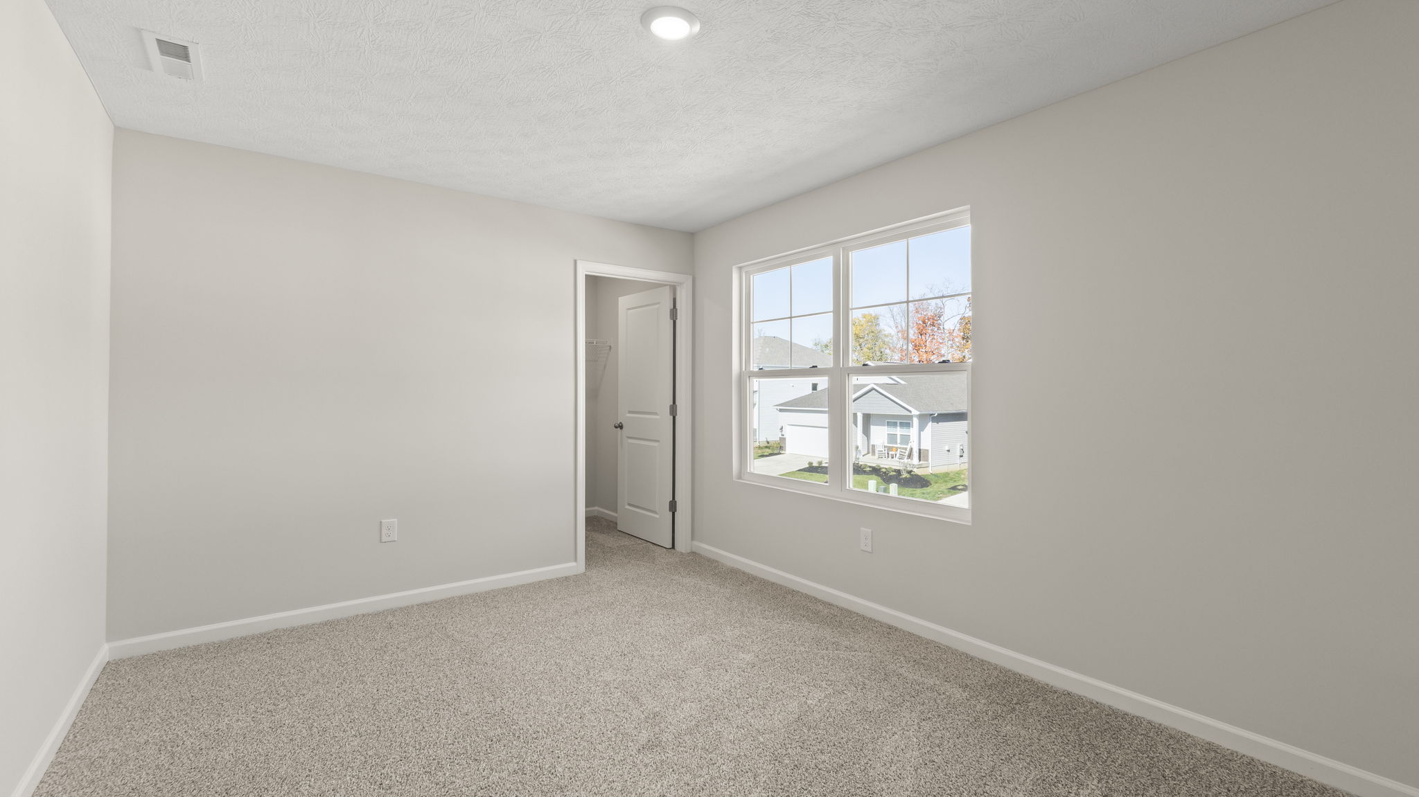 Bedroom with window, puck light, outlets, and door to walk-in closet with shelving.