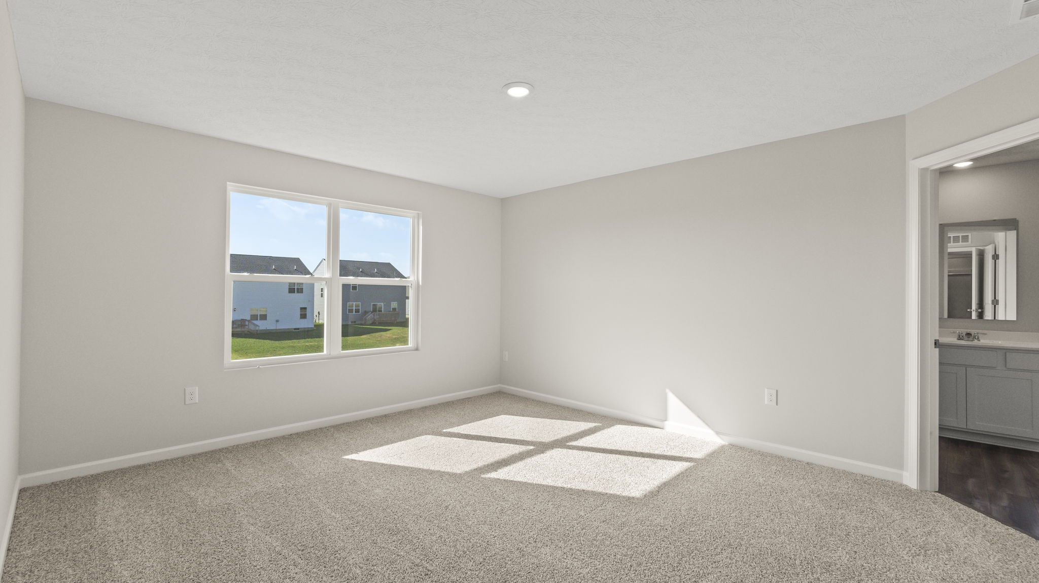 Primary bedroom with outlets, puck light, window, and bathroom suite.