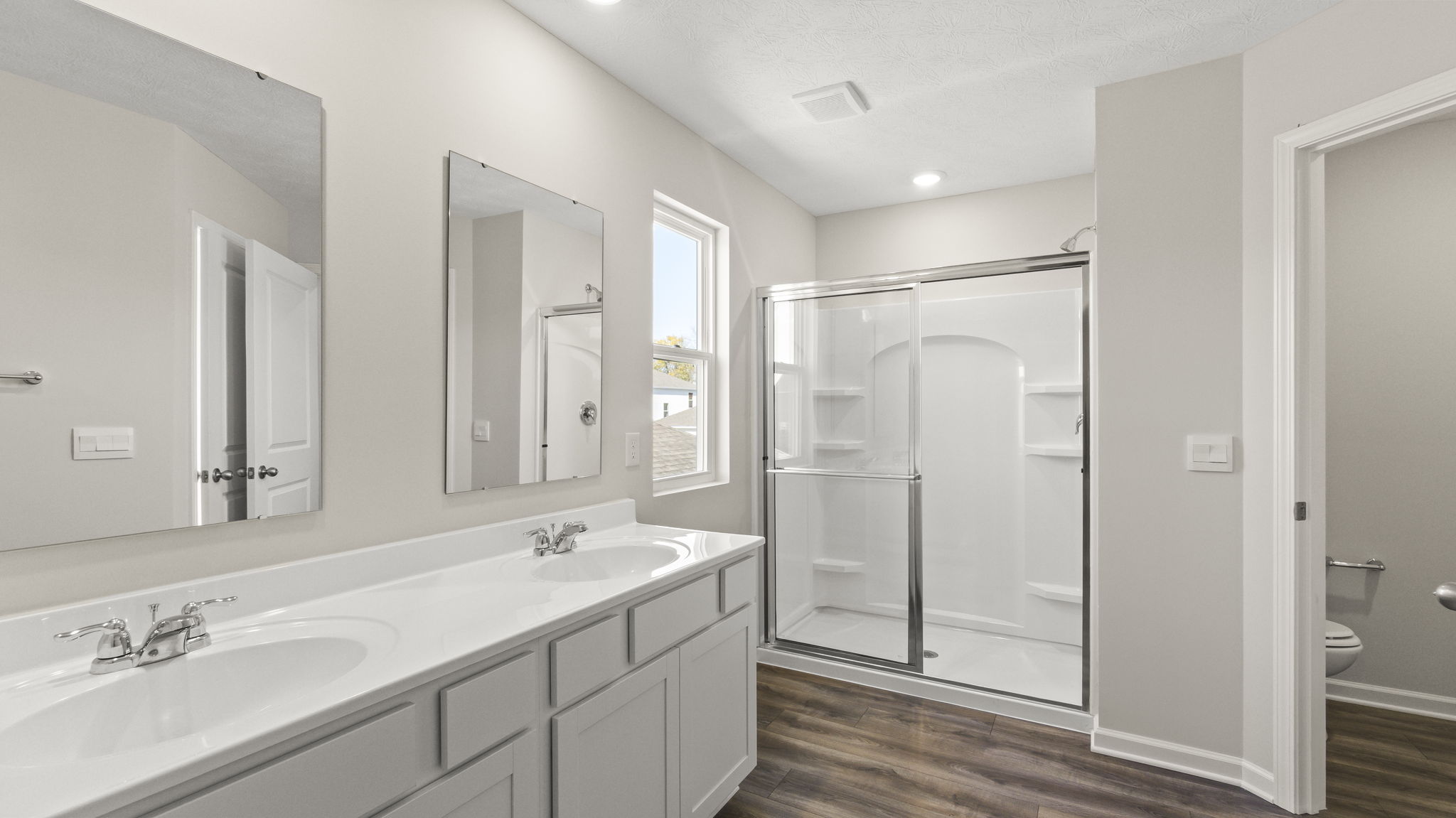 Primary bathroom with dual-sink vanity, mirrors, and walk-in shower.