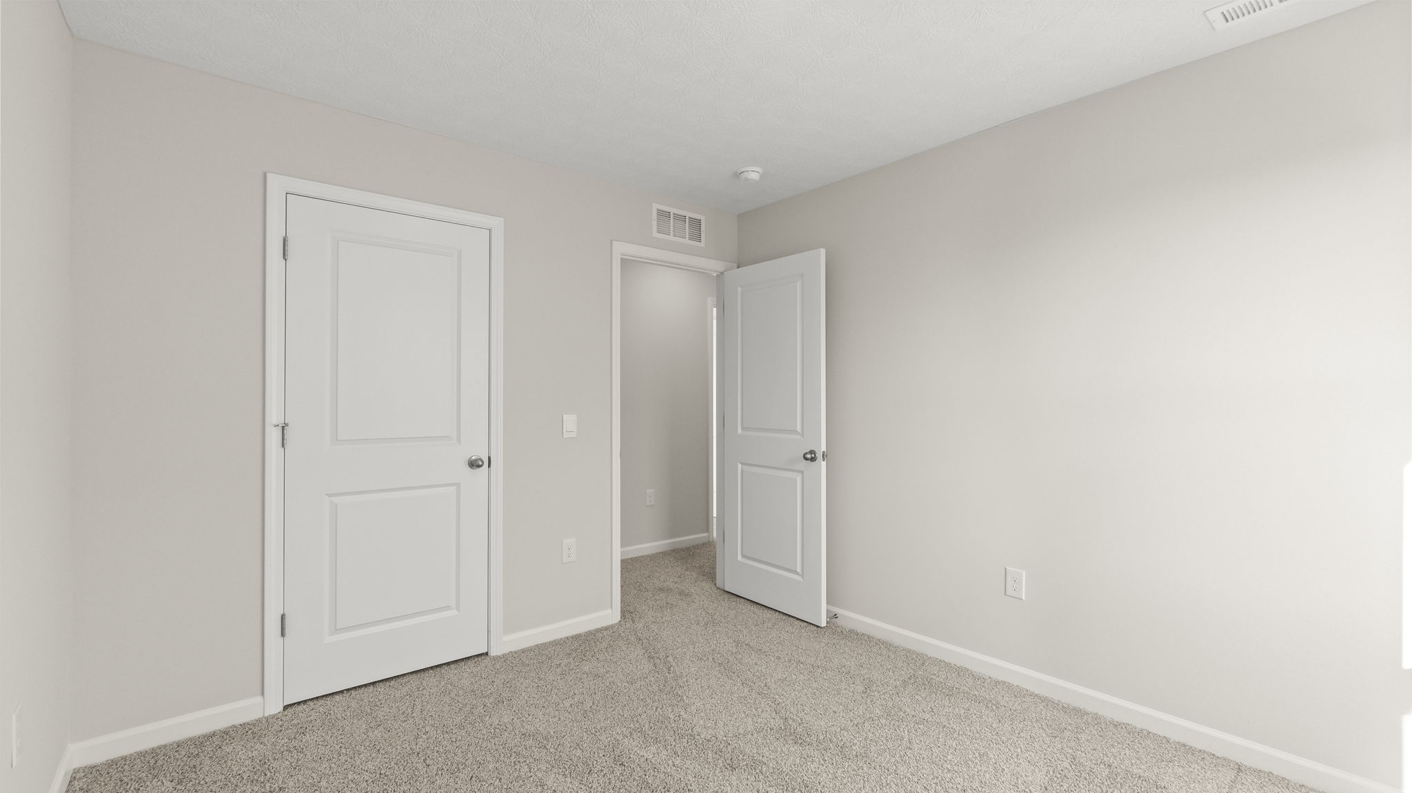 Bedroom with door open to hallway and outlets.