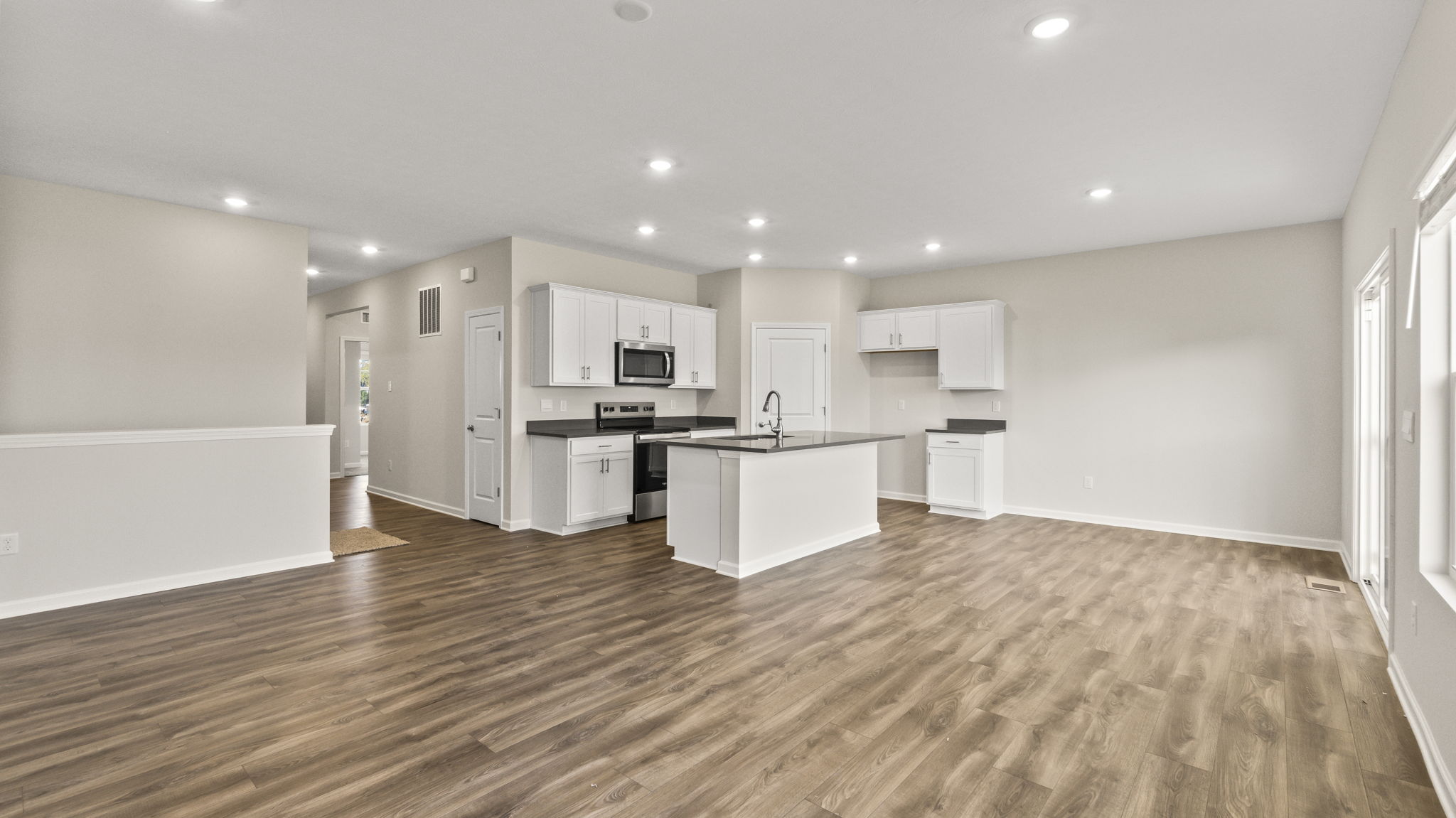 Quarter view of full kitchen and living room.