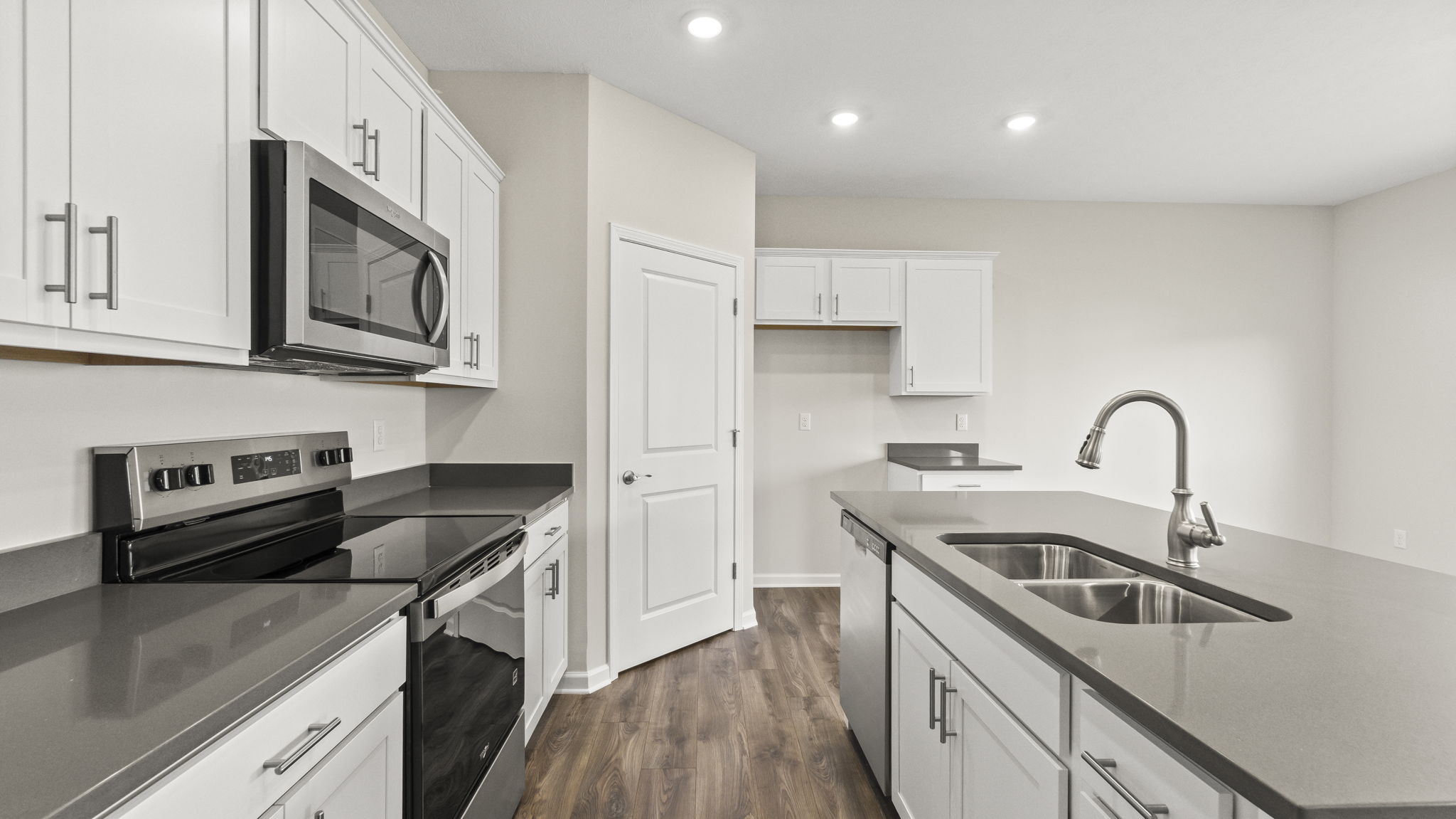 Side view of kitchen with laminate countertops, pantry, and oven range.