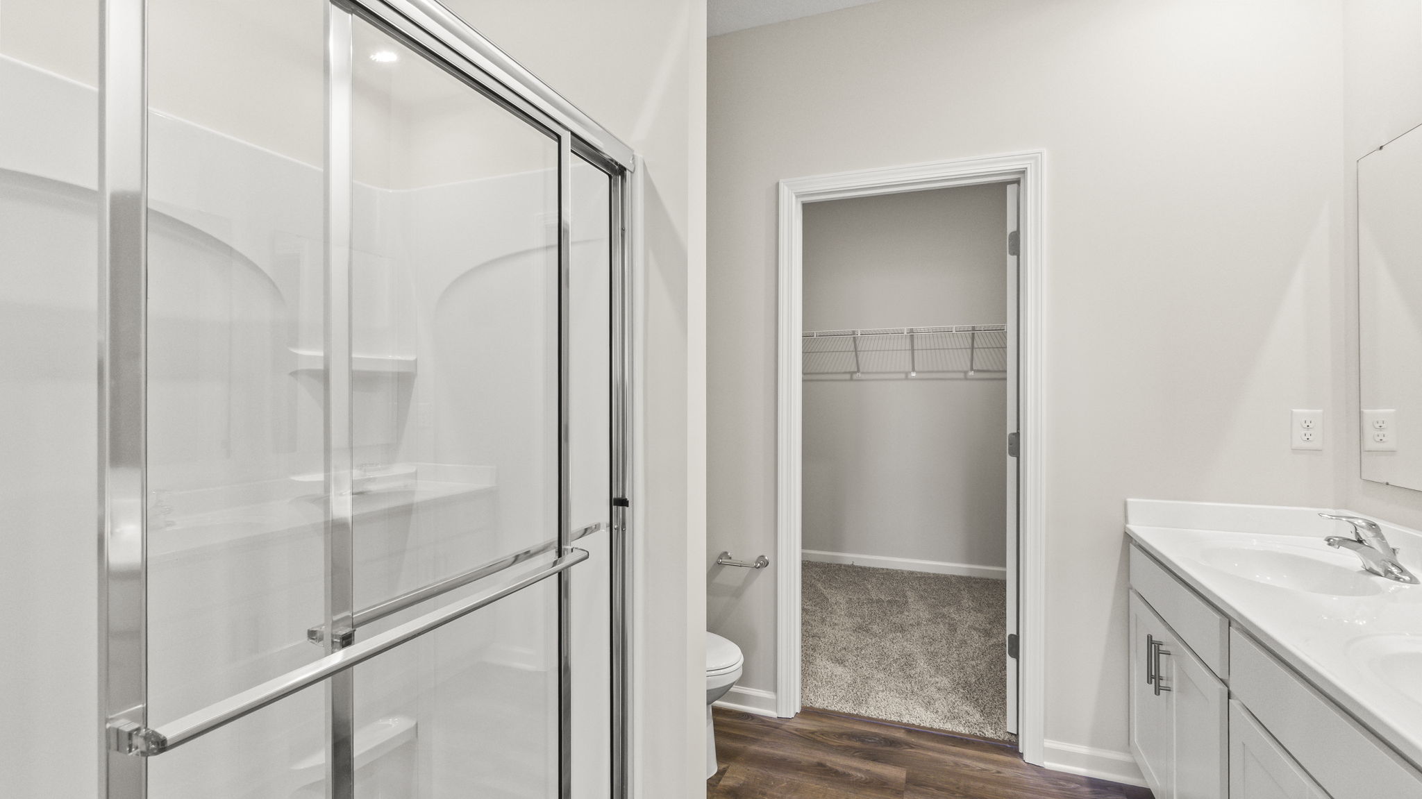 Primary bathroom suite with walk-in shower, storage area, and sink.