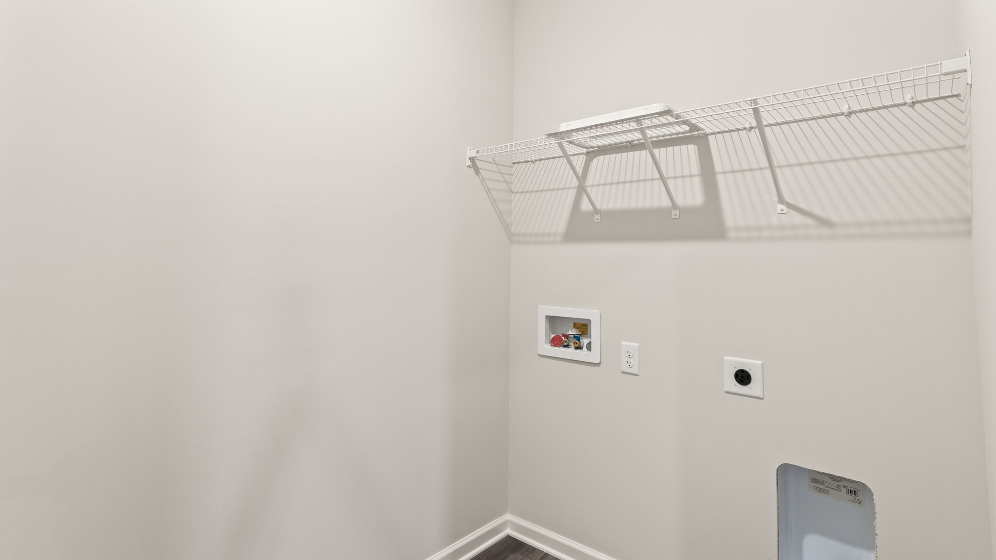 Laundry area with wire shelving and washer/dryer inlets.