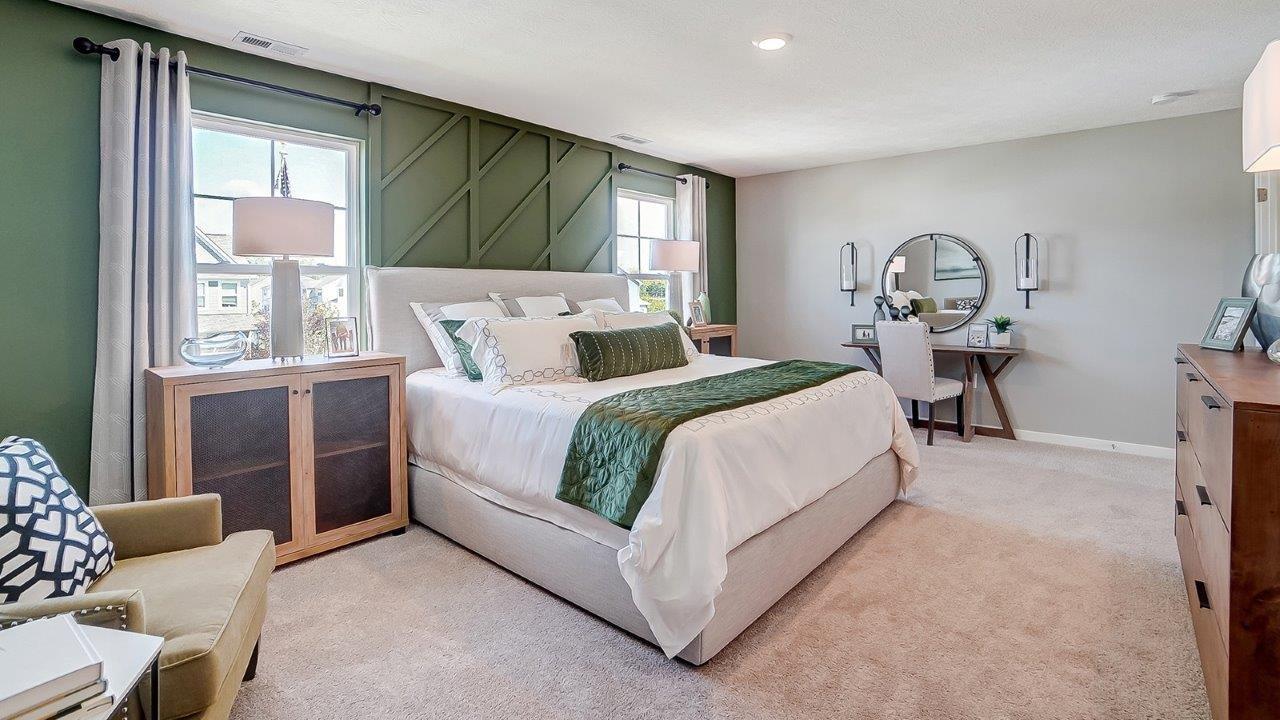 Primary bedroom with large bed and modern art and accents and desk.