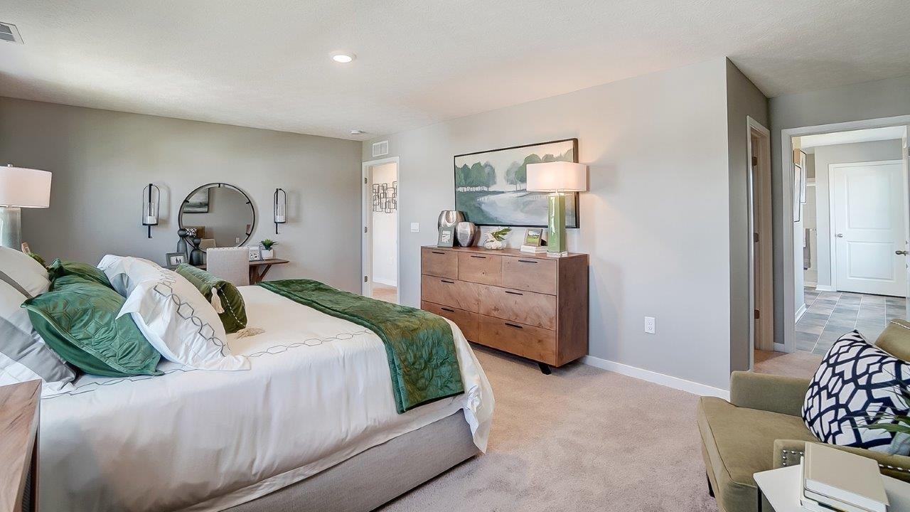 side view of Primary bedroom with dresser and modern art and hallway to private bathroom.
