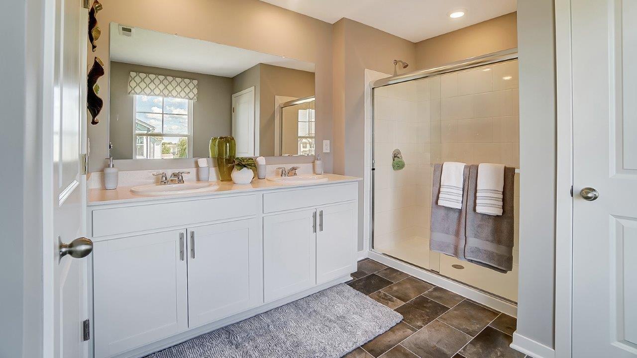 Primary bathroom with dual vanity sinks and shower with white cabinentry.